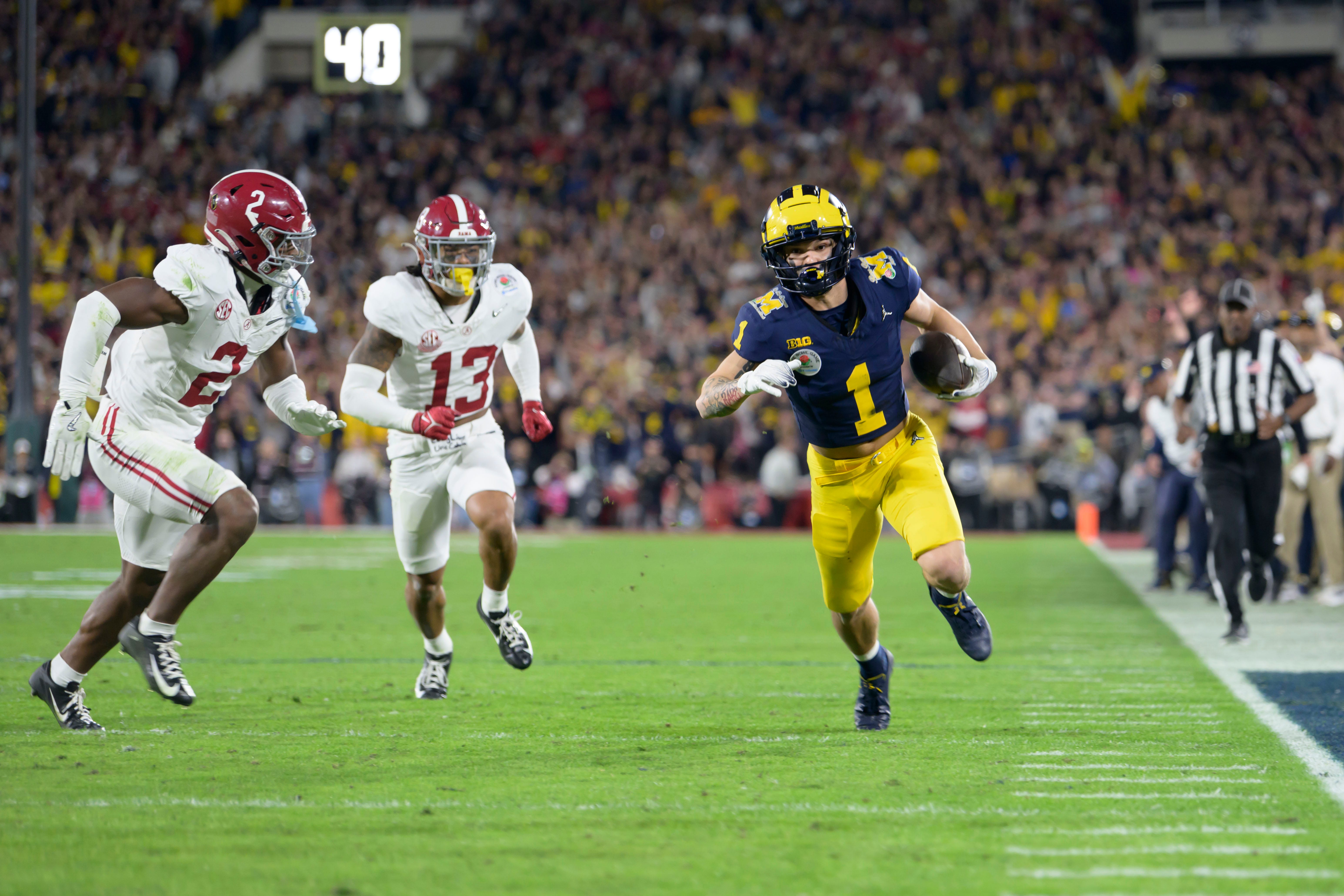 Michigan wide receiver Roman Wilson runs the ball away from Alabama defensive back Caleb Downs, left, and defensive back Malachi Moore during the fourth quarter of the Rose Bowl, in Pasadena, California, January 1, 2024.