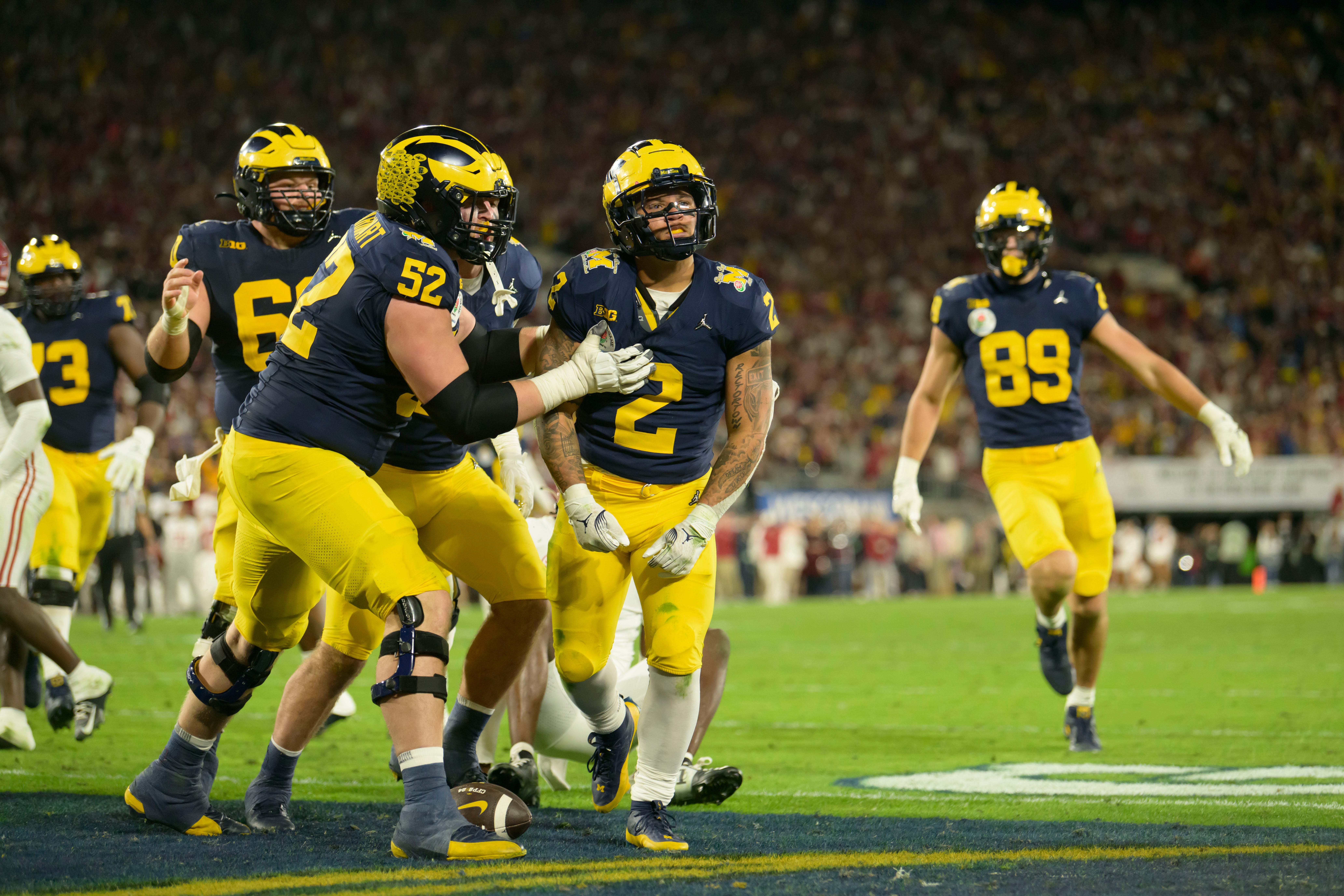 Michigan defensive end Kechaun Bennett (#52) and running back Blake Corum, celebrate after Corum scored a touchdown during the overtime period of the Rose Bowl, in Pasadena, California, January 1, 2024.