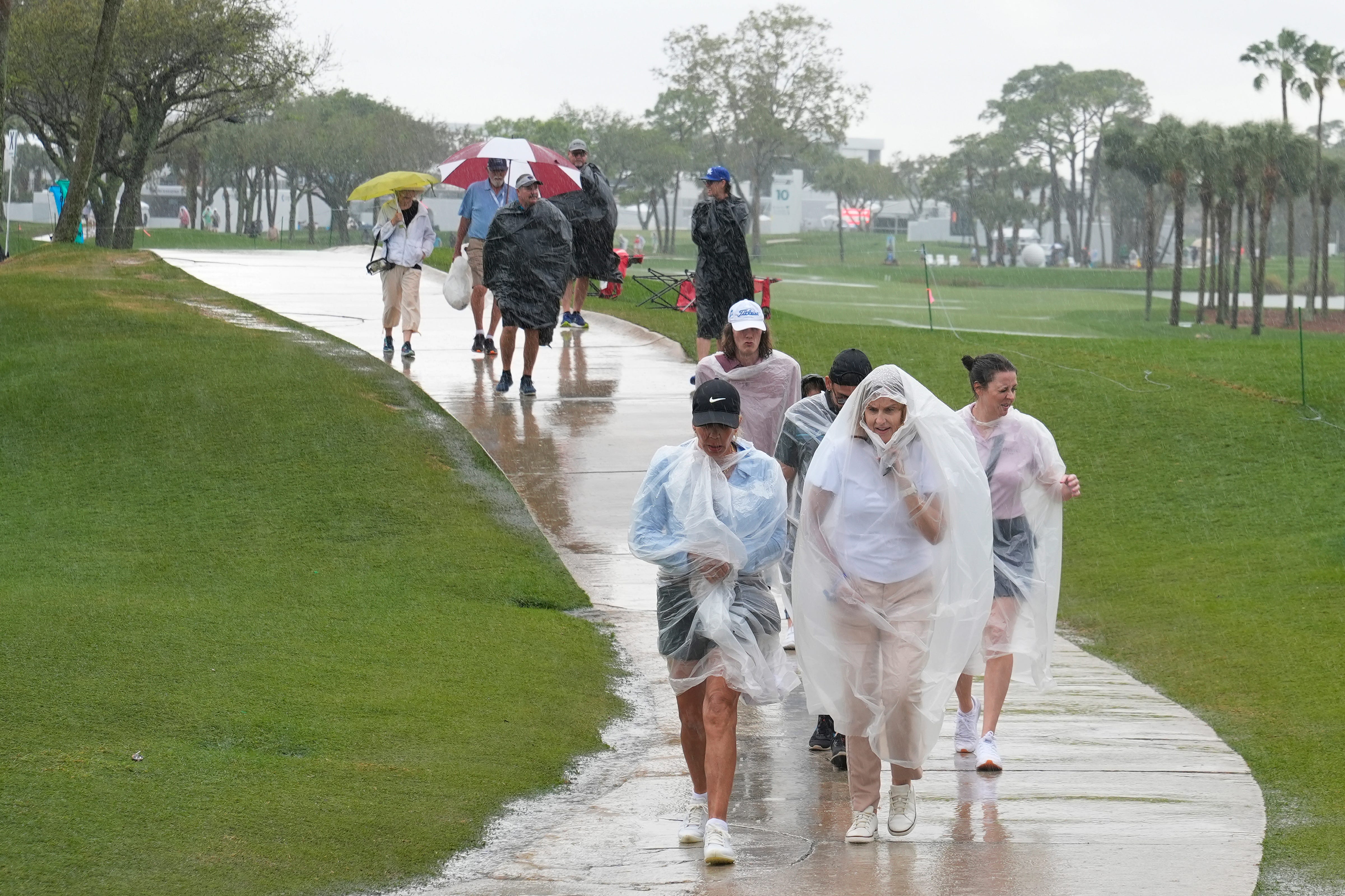 Spectators exit the course as heavy rain delays the final round of the Cognizant Classic golf tournament, Sunday, March 3, 2024, in Palm Beach Gardens, Fla.