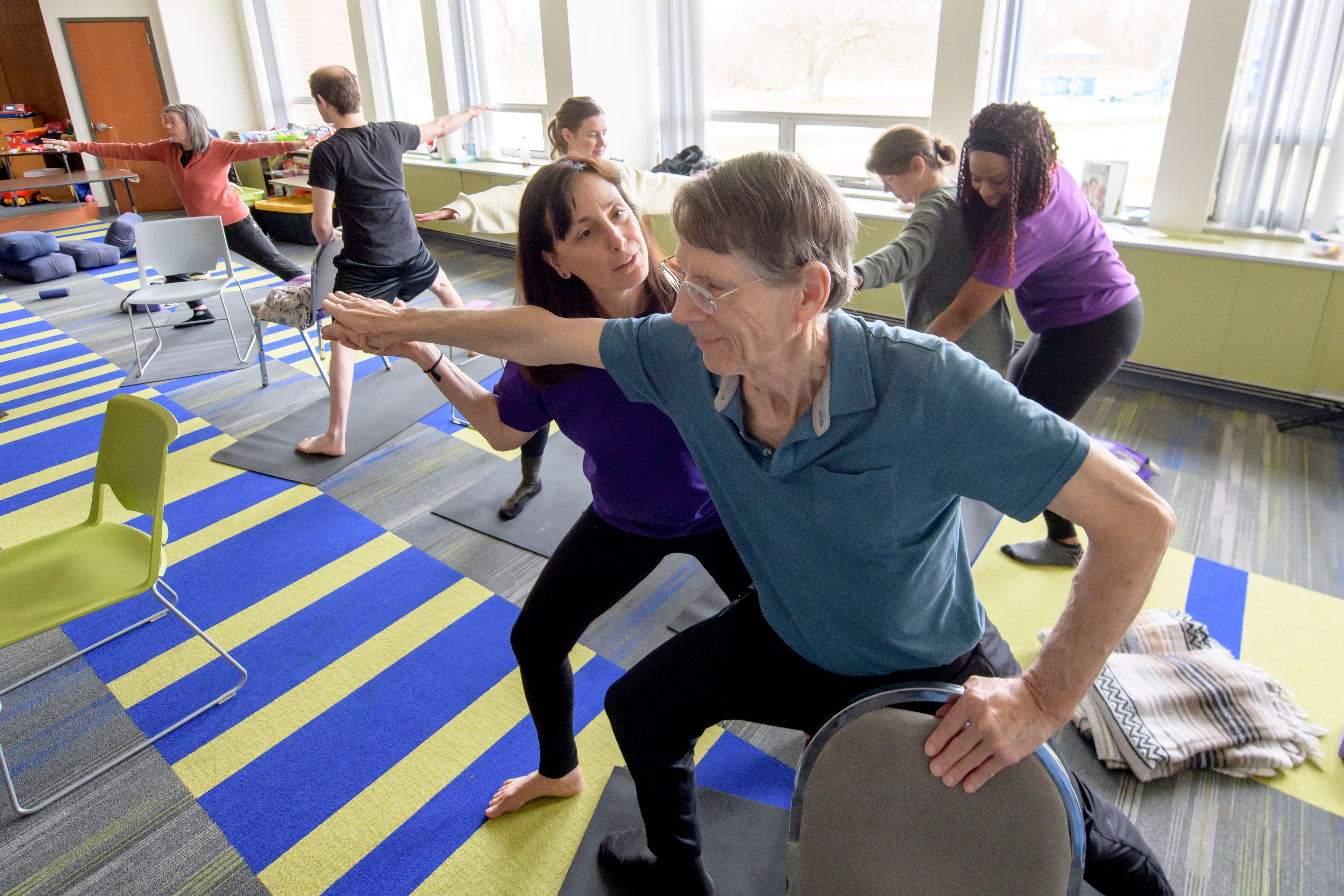 Instructor Mindy Eisenberg, center, assists Roger Horsley, of St. Clair Shores during a Yoga Moves Parkinson's class, at Congregation Shaarey Zedek, March 6, 2024. The Kirk Gibson Foundation started the program to offer free yoga classes specifically designed to help people living with Parkinson's Disease.