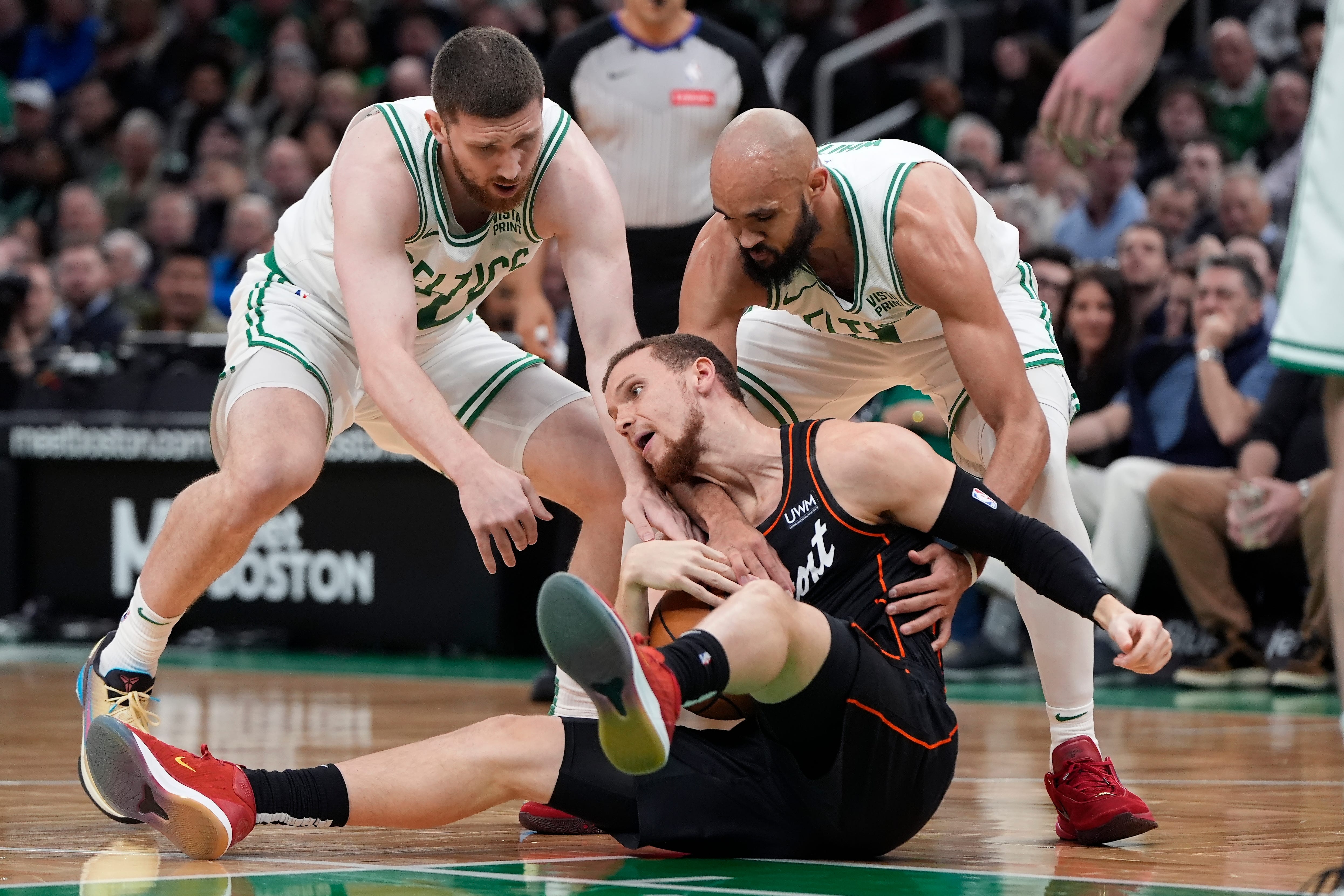 Boston Celtics' Svi Mykhailiuk, left, and Derrick White, right, battle Detroit Pistons' Malachi Flynn, center, for the ball during the first half.