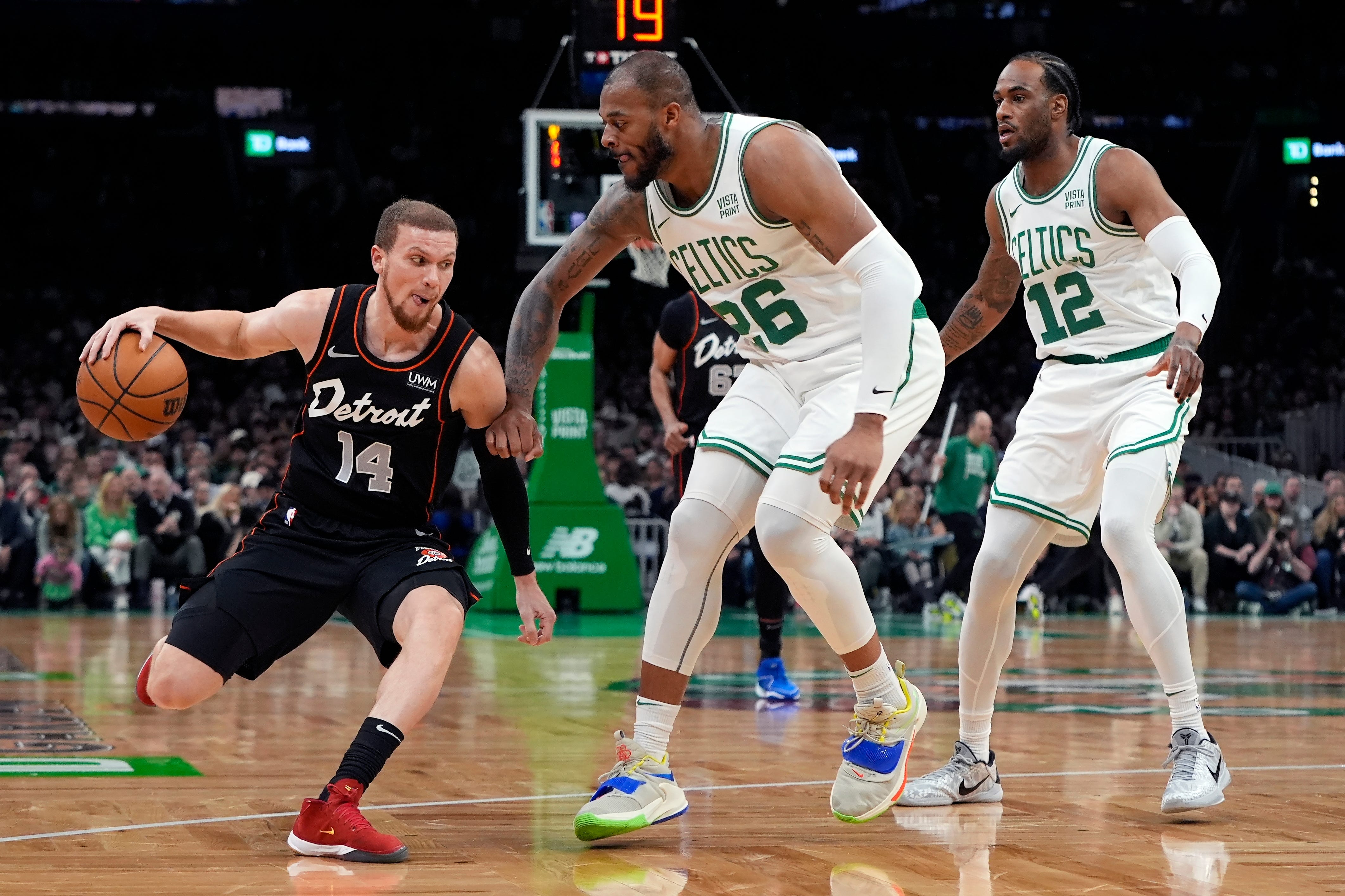 Boston Celtics' Xavier Tillman (26) and Oshae Brissett (12) defend against Detroit Pistons' Malachi Flynn (14) during the first half.