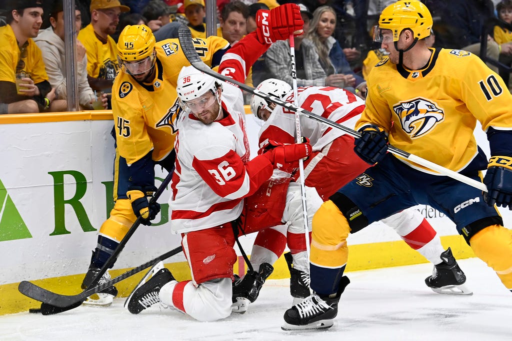 Predators defenseman Alexandre Carrier (45) battles for the puck with Red Wings right wing Christian Fischer (36) and center Michael Rasmussen (27) during the first period.
