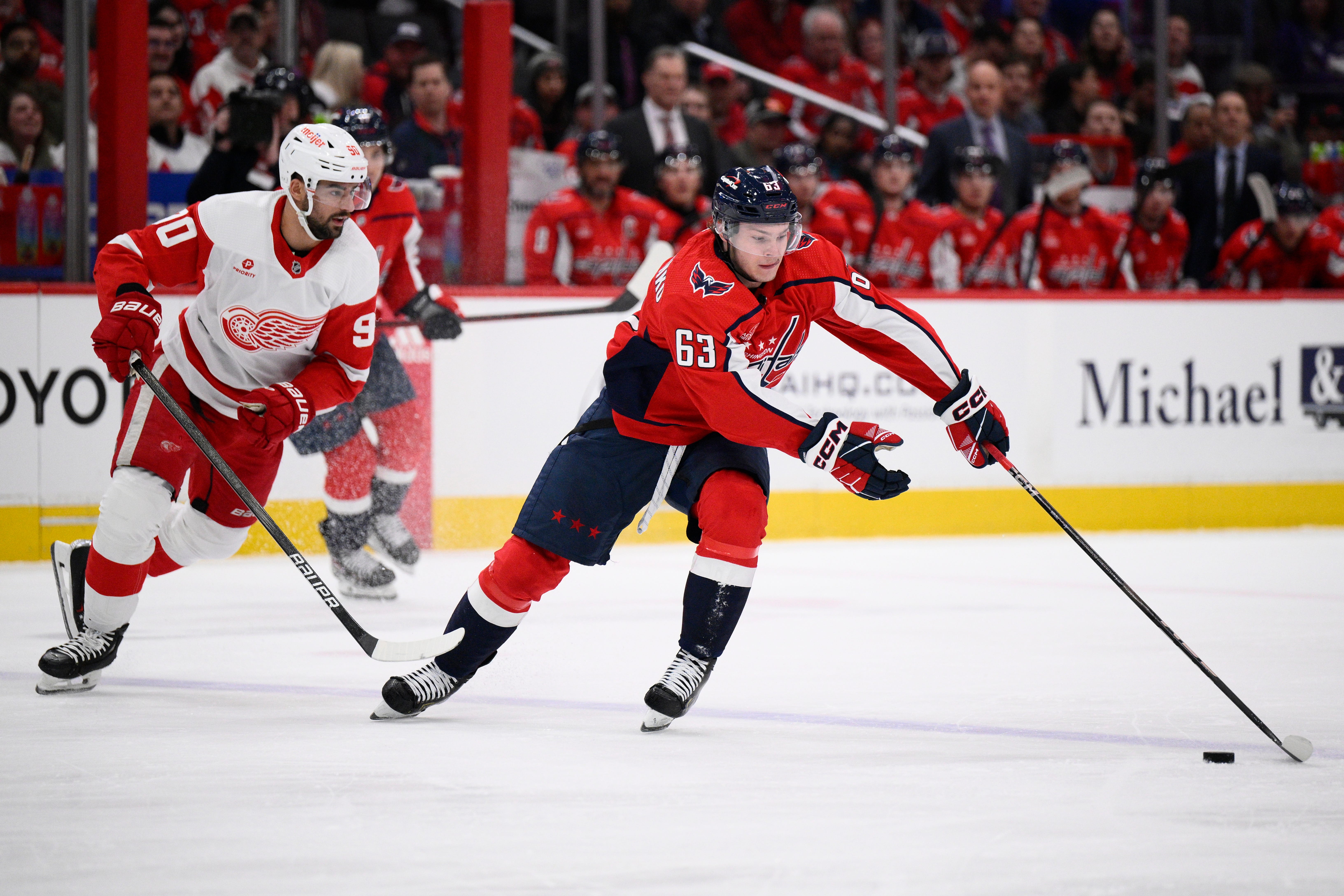 Washington Capitals left wing Ivan Miroshnichenko (63) reaches for the puck against Detroit Red Wings center Joe Veleno (90) during the first period of an NHL hockey game, Tuesday, March 26, 2024, in Washington. The Capitals win, 4 to 3 in OT.