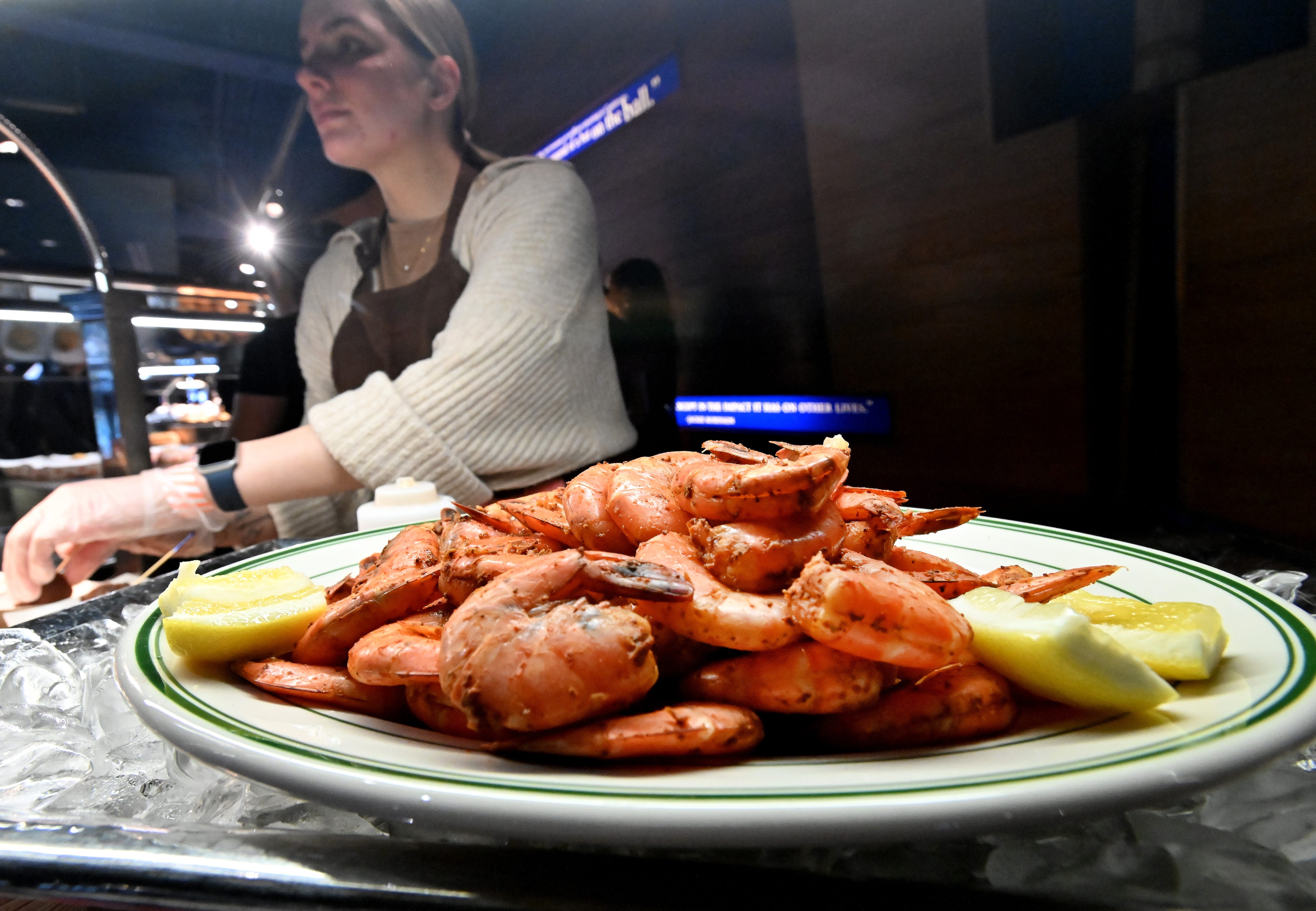 Voyager restaurant's Emily Cameron serving up peel and eat shrimp, served with a spicy sauce, during the "what's new" event at Comerica Park for the 2024 season.