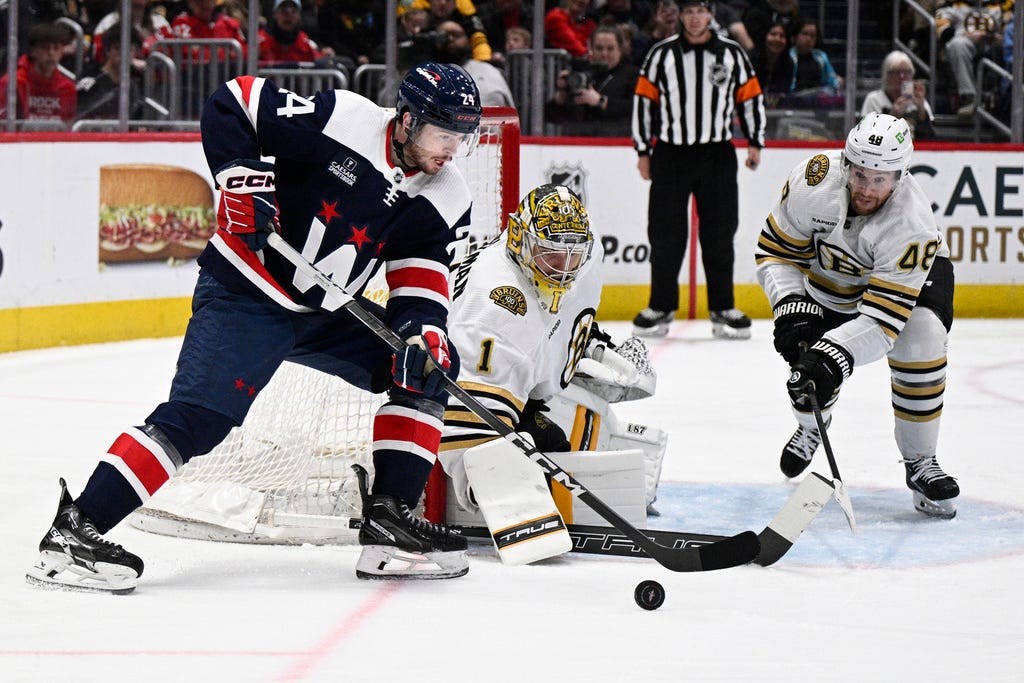 Capitals center Connor McMichael (24) and Bruins goaltender Jeremy Swayman (1) and defenseman Matt Grzelcyk (48) vie for the puck during the second period of Saturday's game in Washington.