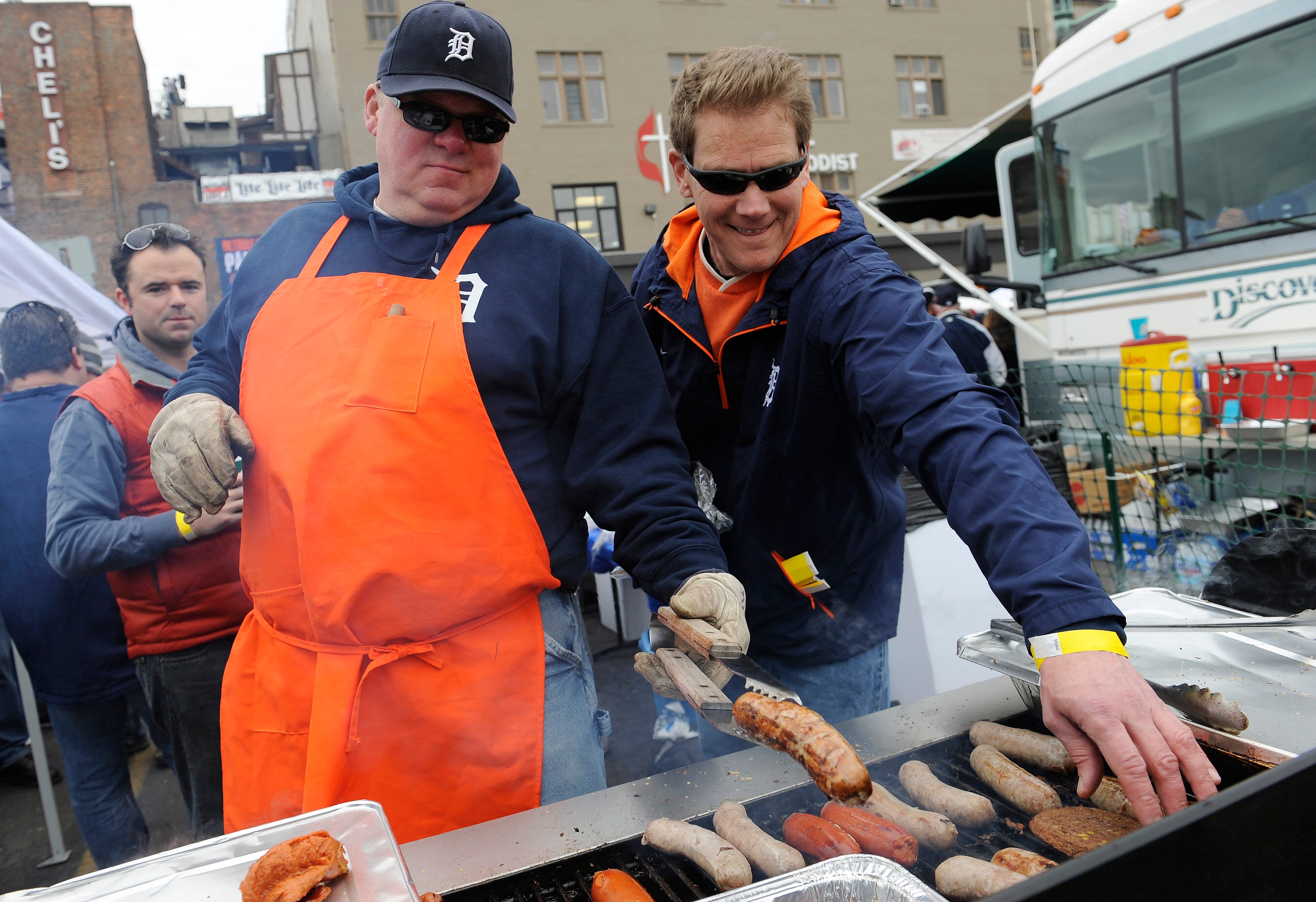l-r, John Stasie of Commerce Twp. and Douglas Wehner of Ferndale grill some brats and hot sausage during their tailgate party. Detroit Tigers Opening Day at Comerica Park, Detroit, MI.