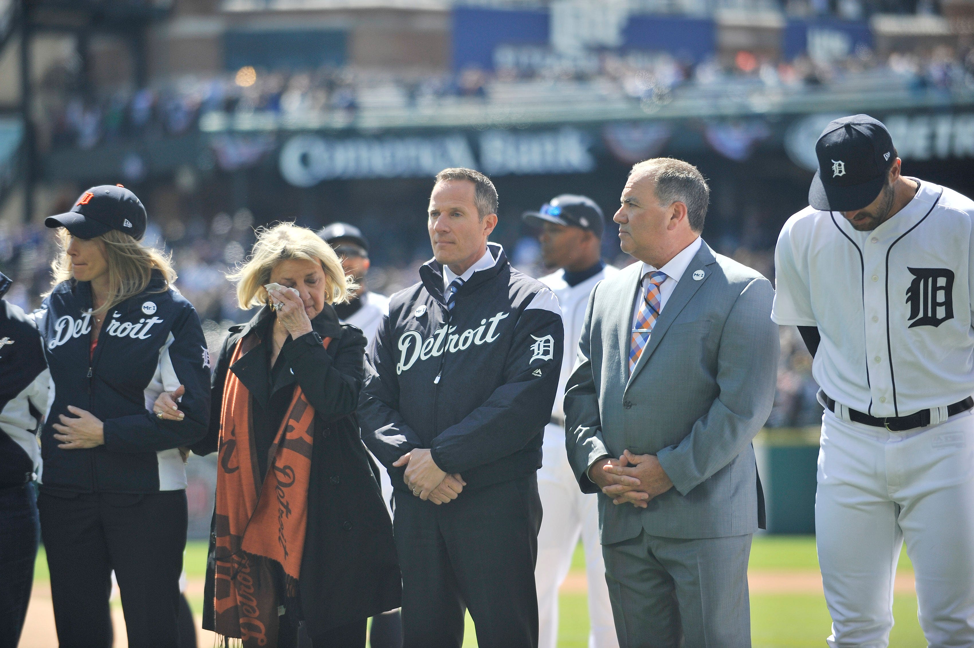 Marian Ilitch wipes away a tear standing with her son, Chris Ilitch, next to Al Avila, right, Tigers executive vice president of baseball operations and general manager after a moment of silence during the tribute to Michael Ilitch before the game. Detroit Tigers vs Boston Red Sox at Tigers Opening Day at Comerica Park in Detroit on April 7, 2017.