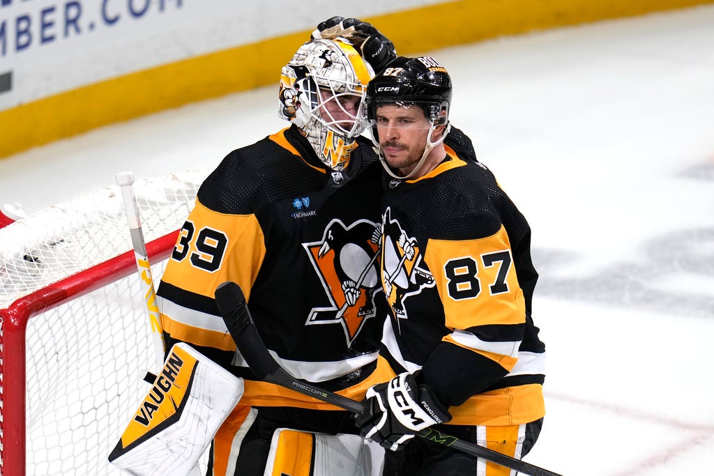 Penguins' Sidney Crosby (87) celebrates with goaltender Alex Nedeljkovic following a 5-4 victory against the Lightning in Pittsburgh on Saturday.