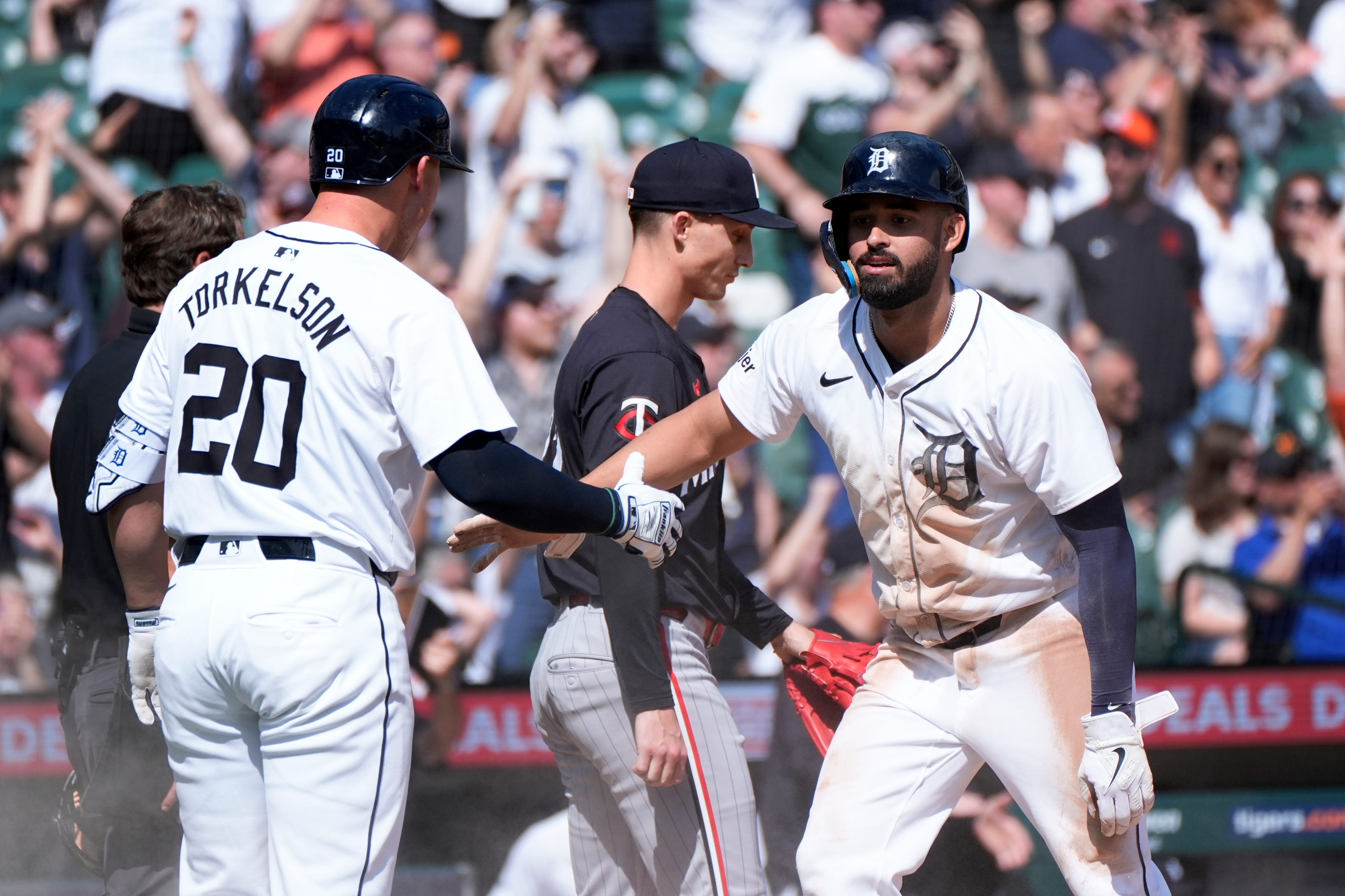 Detroit Tigers' Riley Greene, right, celebrates scoring with Spencer Torkelson (20) as Minnesota Twins pitcher Griffin Jax (22) walks back to the mound in the eighth inning of a baseball game, Sunday, April 14, 2024, in Detroit. (AP Photo/Paul Sancya)