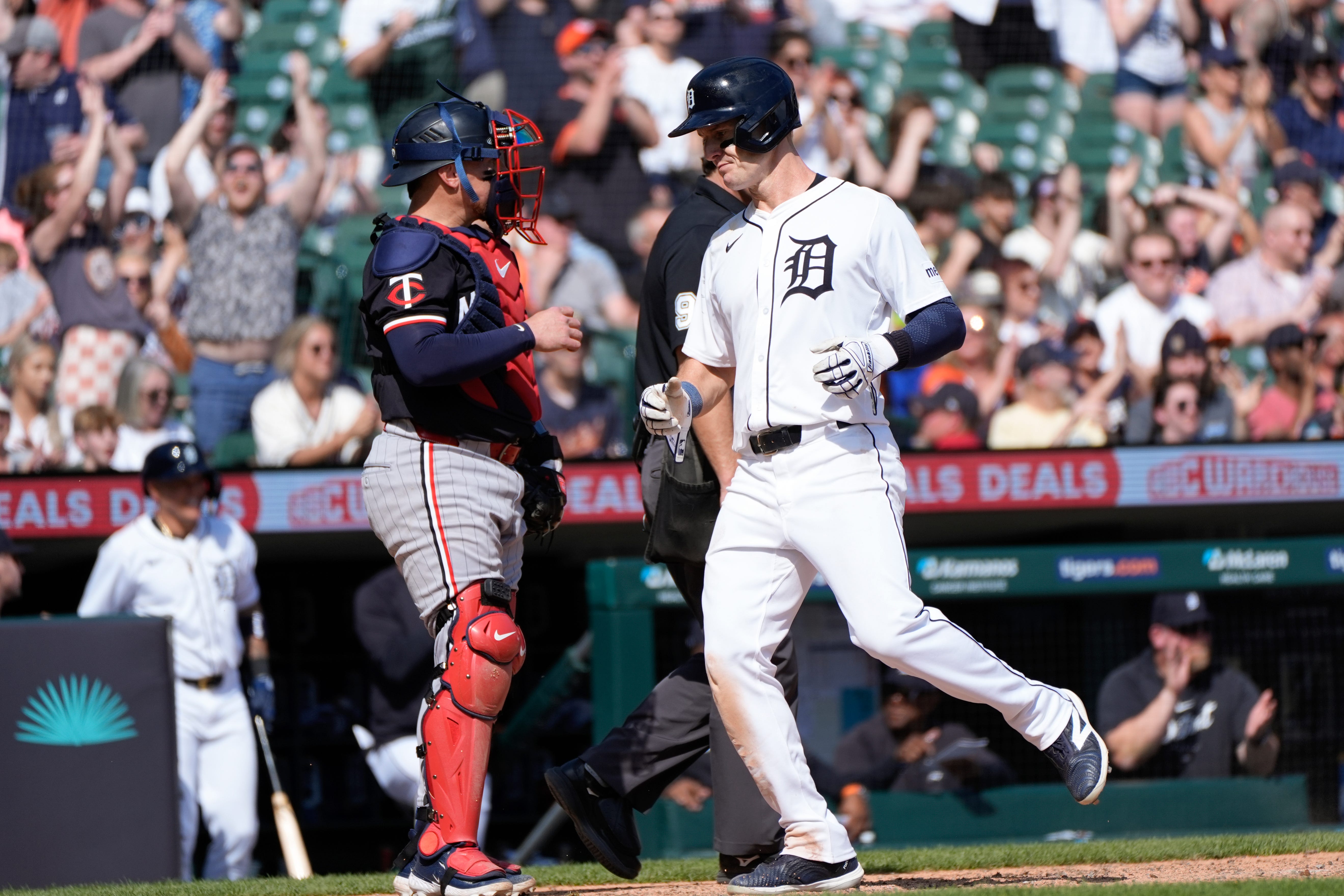 Detroit Tigers' Mark Canha, right, scores as Minnesota Twins catcher Christian Vázquez looks on in the eighth inning of a baseball game, Sunday, April 14, 2024, in Detroit. (AP Photo/Paul Sancya)