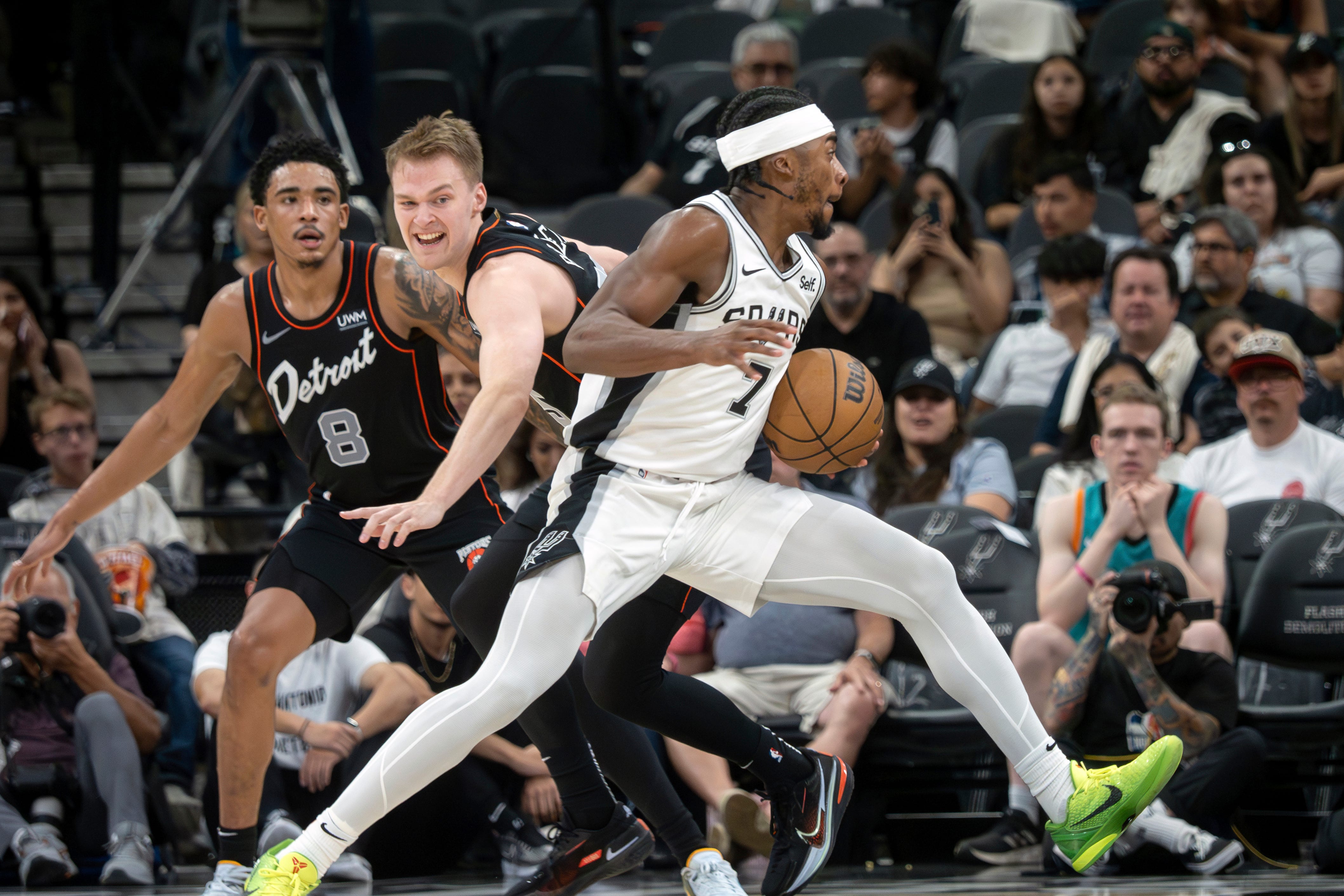 San Antonio Spurs guard David Duke, Jr., right, drives the ball against Detroit Pistons guards Buddy Boeheim, center, and Jared Rhoden, left, during the second half of an NBA basketball game, Sunday, April 14, 2024, in San Antonio. (AP Photo/Michael Thomas)