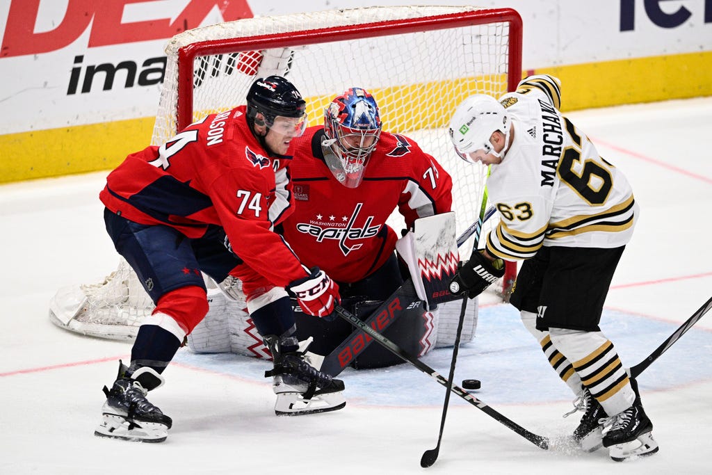 Bruins left wing Brad Marchand (63) battles for the puck against Capitals defenseman John Carlson (74) and goaltender Charlie Lindgren (79) during the third period on Monday in Washington.