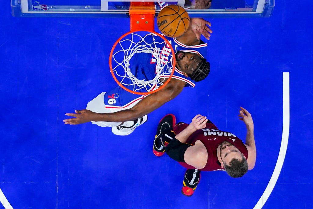 76ers' Joel Embiid, left, shoots over Heat's Kevin Love during the first half of the NBA play-in tournament in Philadelphia.