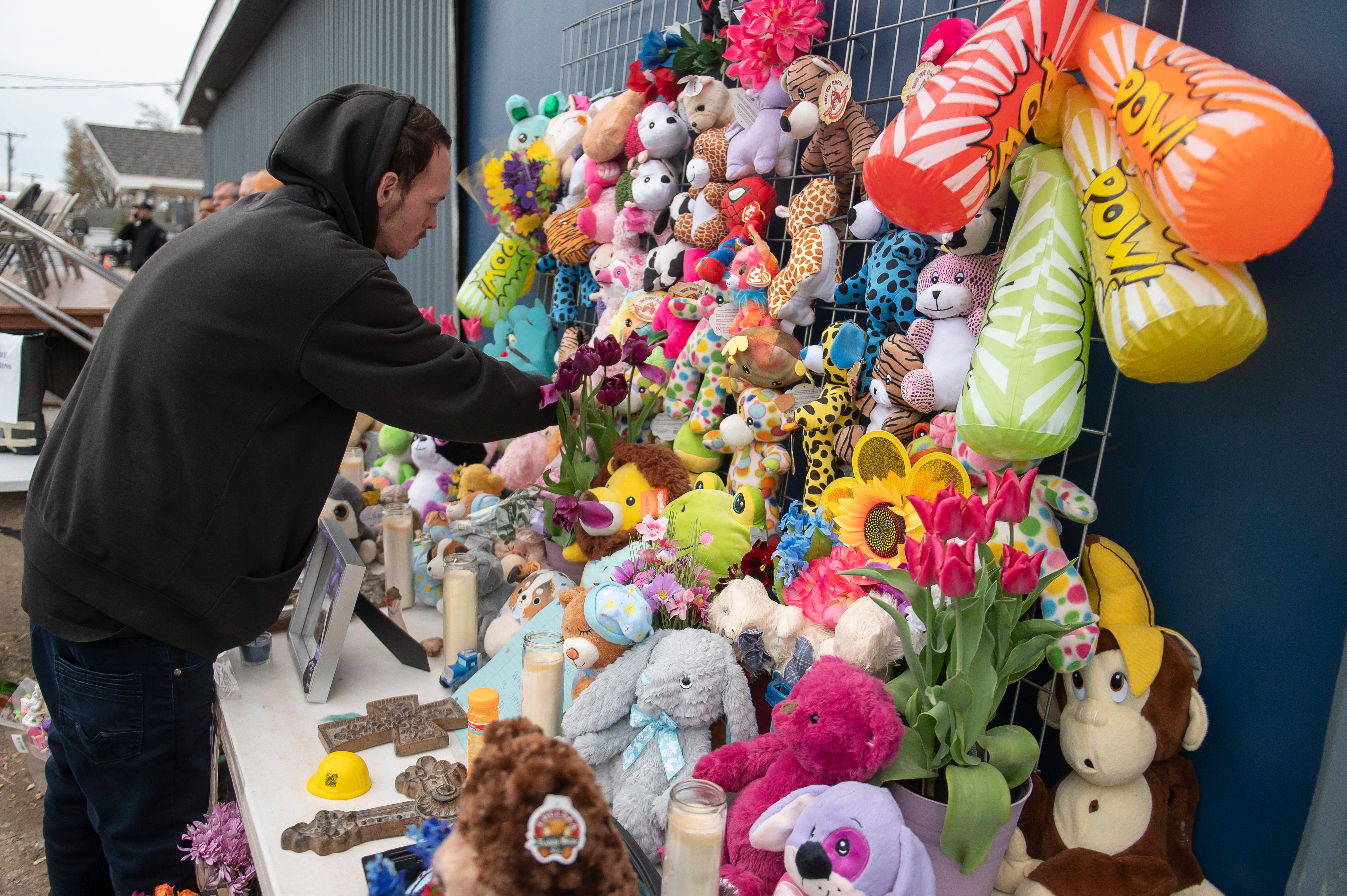 Nicholas Phillips places a stuffed animal onto a shrine in remembrance of his niece and nephew, Alanah Phillips, 8, and Zayn Phillips, 4, before a vigil in their honor on Friday, April 26, 2024, at the Swan Boat Club in Newport, Michigan.