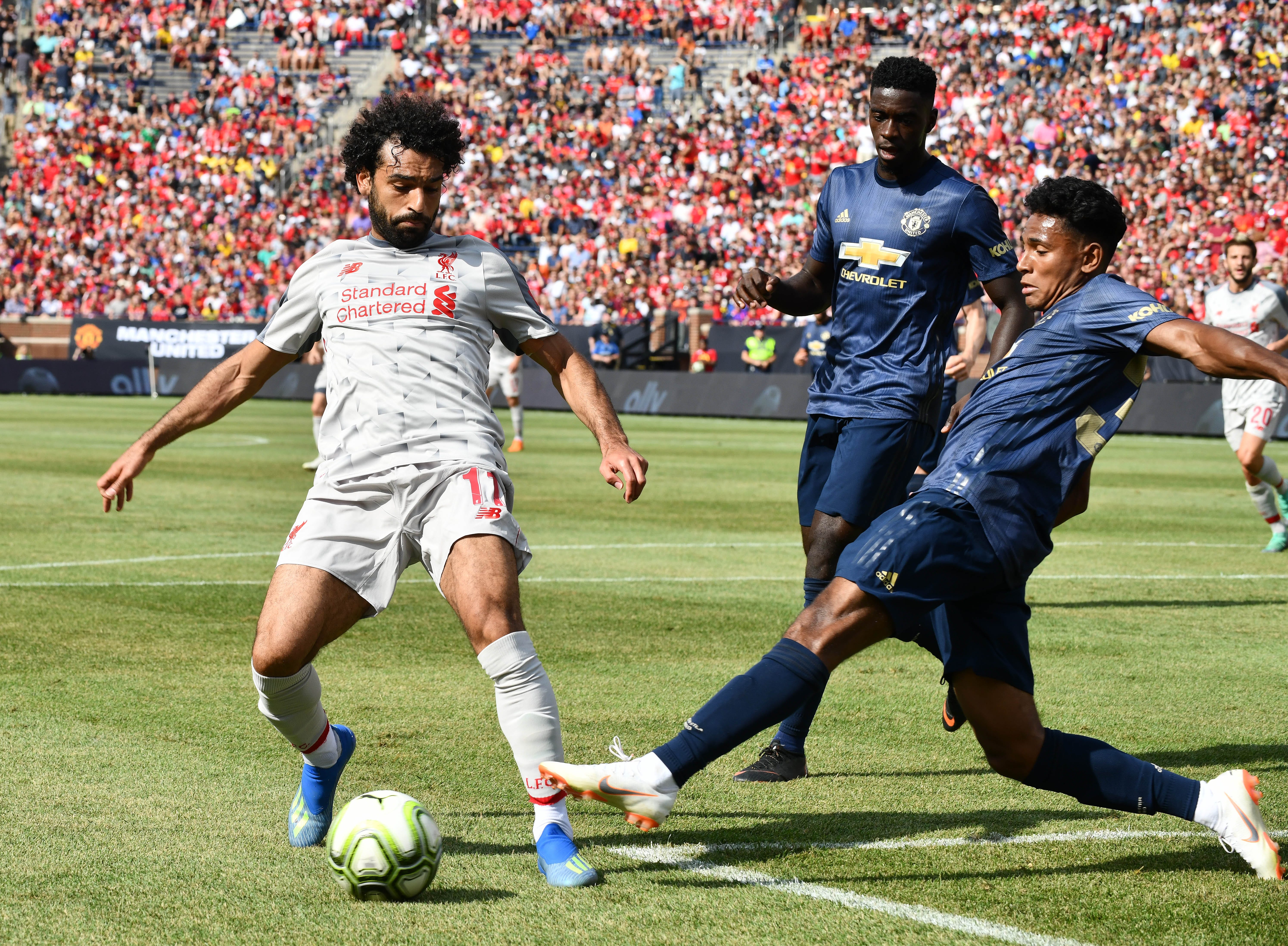 Liverpool's Mohamed Salah chases down a loose ball in front of Manchester United's net with Demetri Mitchell defending in the first half.