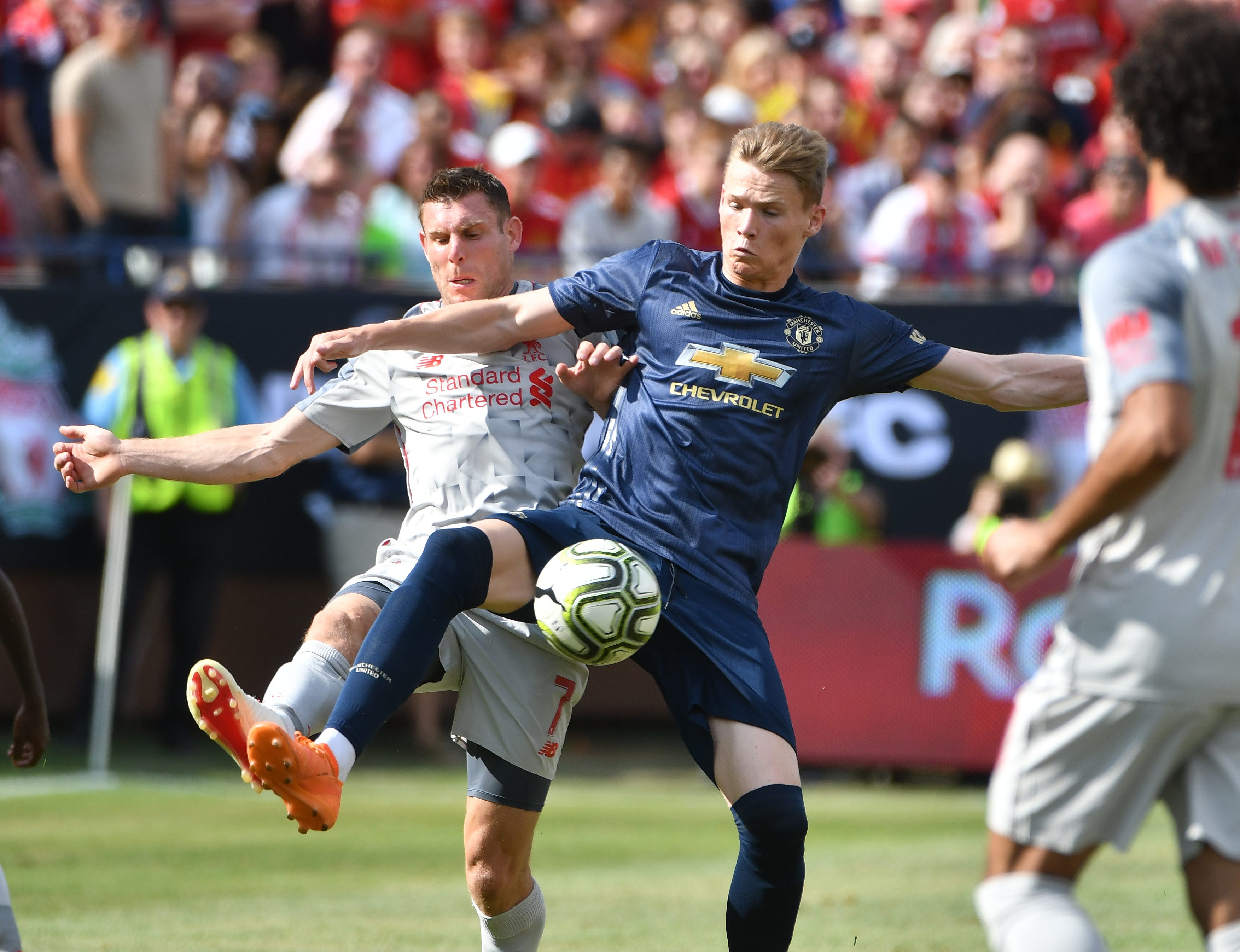 Liverpool's James Milner and Manchester's Scott McTominay battle over a ball in the first half.