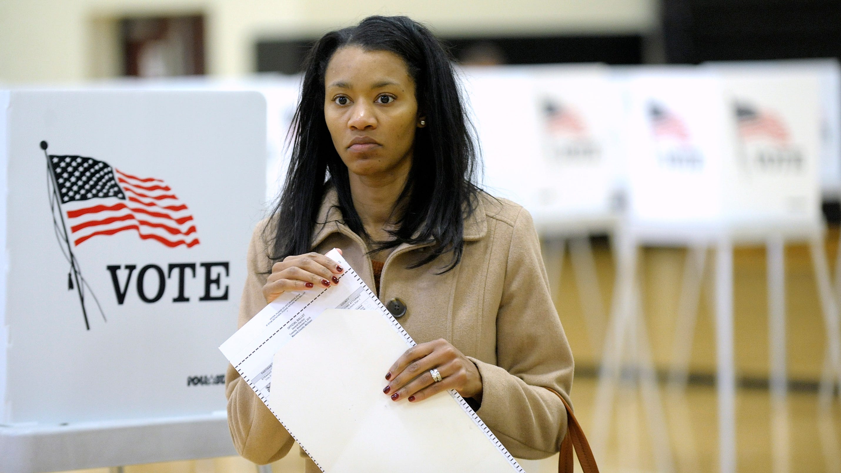 Chawanne Burns, 38, of Macomb Twp., prepares to cast her ballot at L'Anse Creuse Middle School as precinct workers facilitate their ballot processing, Tuesday afternoon, November 8, 2016.