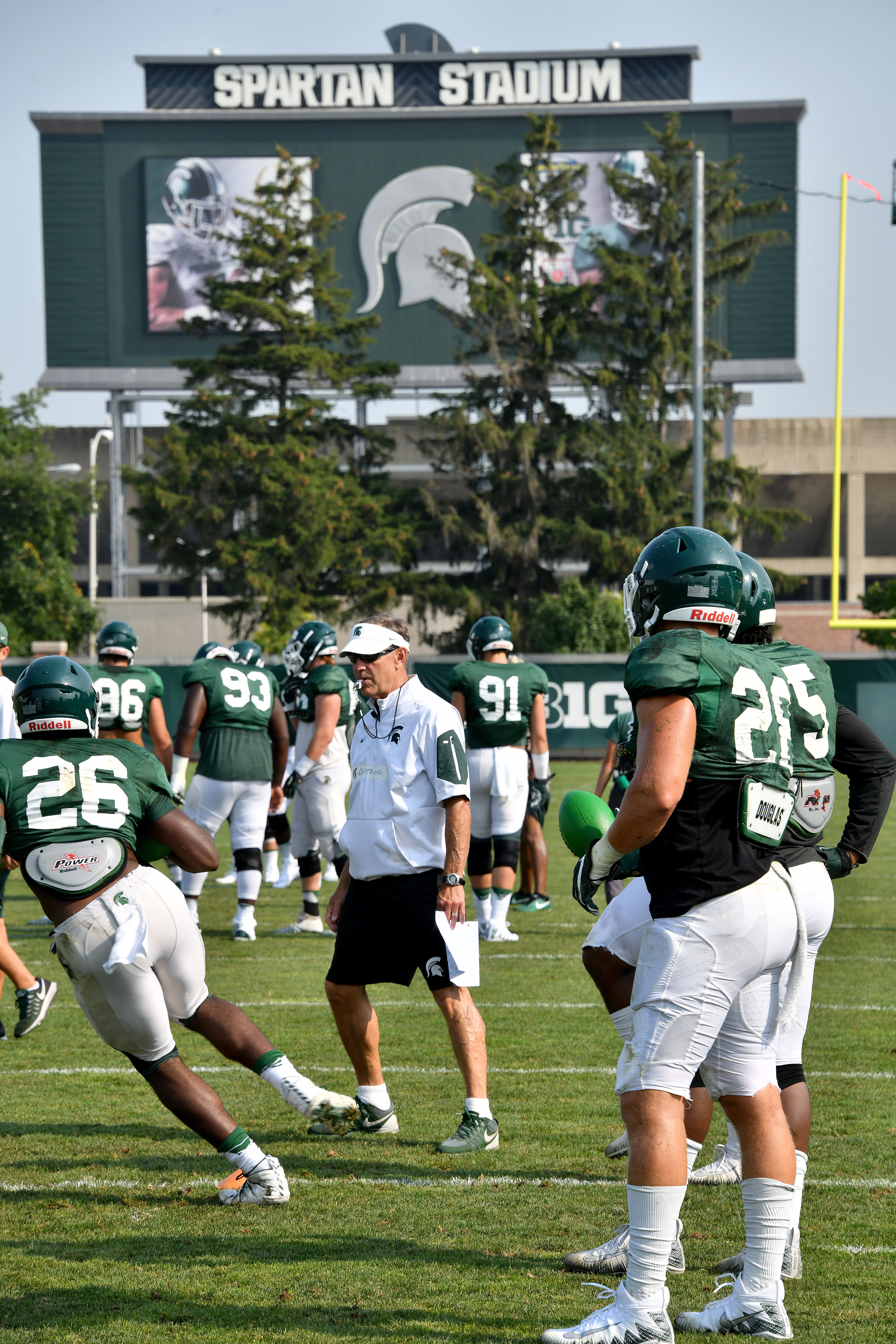 Michigan State head coach Mark Dantonio watches his players go through defensive drills during a morning practice session at MSU's football practice facility on Tuesday, Aug. 14, 2018.  In the background, Spartan Stadium awaits the season opener, Aug. 31 against Utah State.