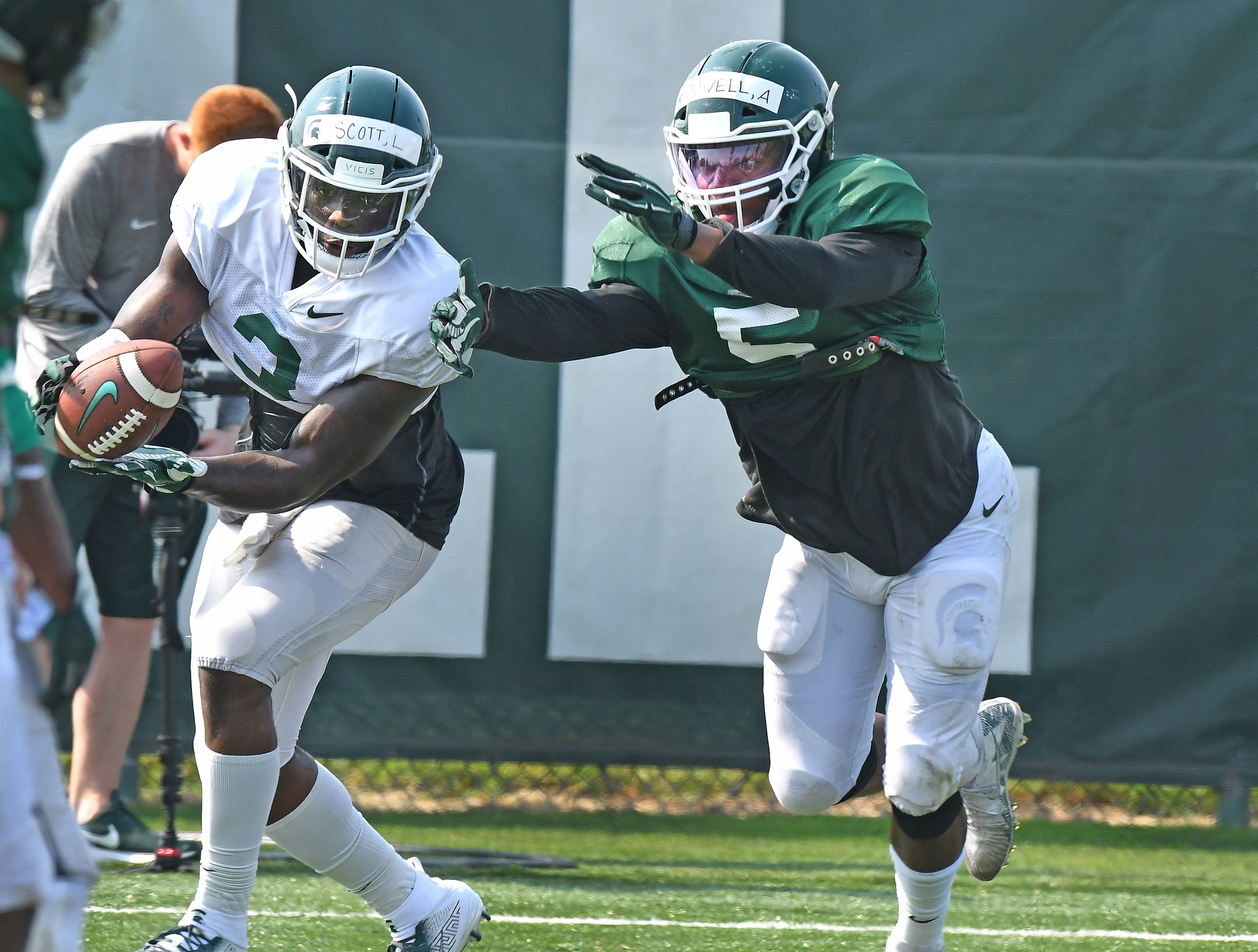 Michigan State veteran running back LJ Scott catches a pass in the end zone in spite of linebacker Andrw Dowell (5) .
