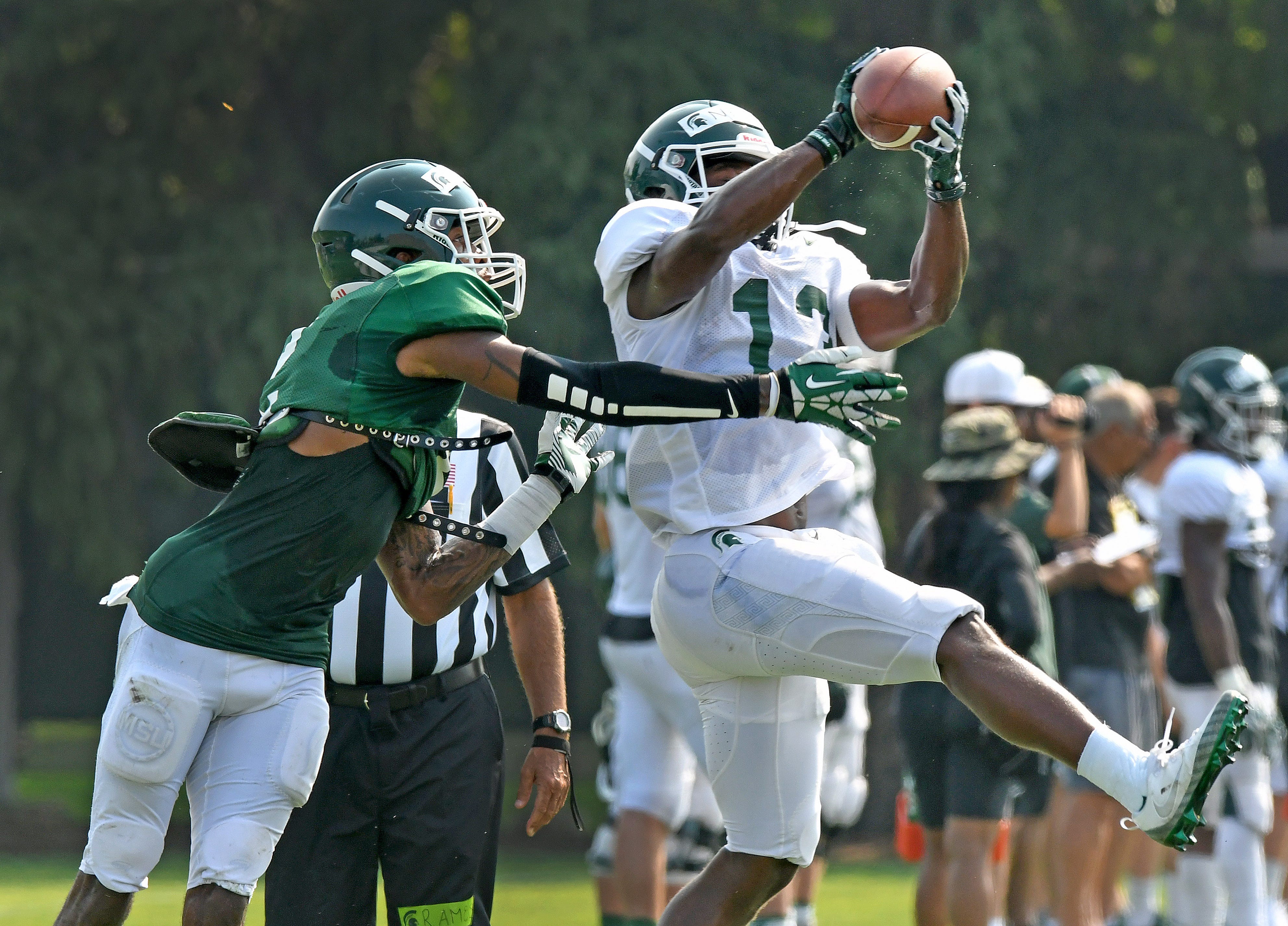 Michigan State recevier Laress Nelson (13) pulls in a pass in spite of teammate Justin Layne's efforts during a morning practice session.