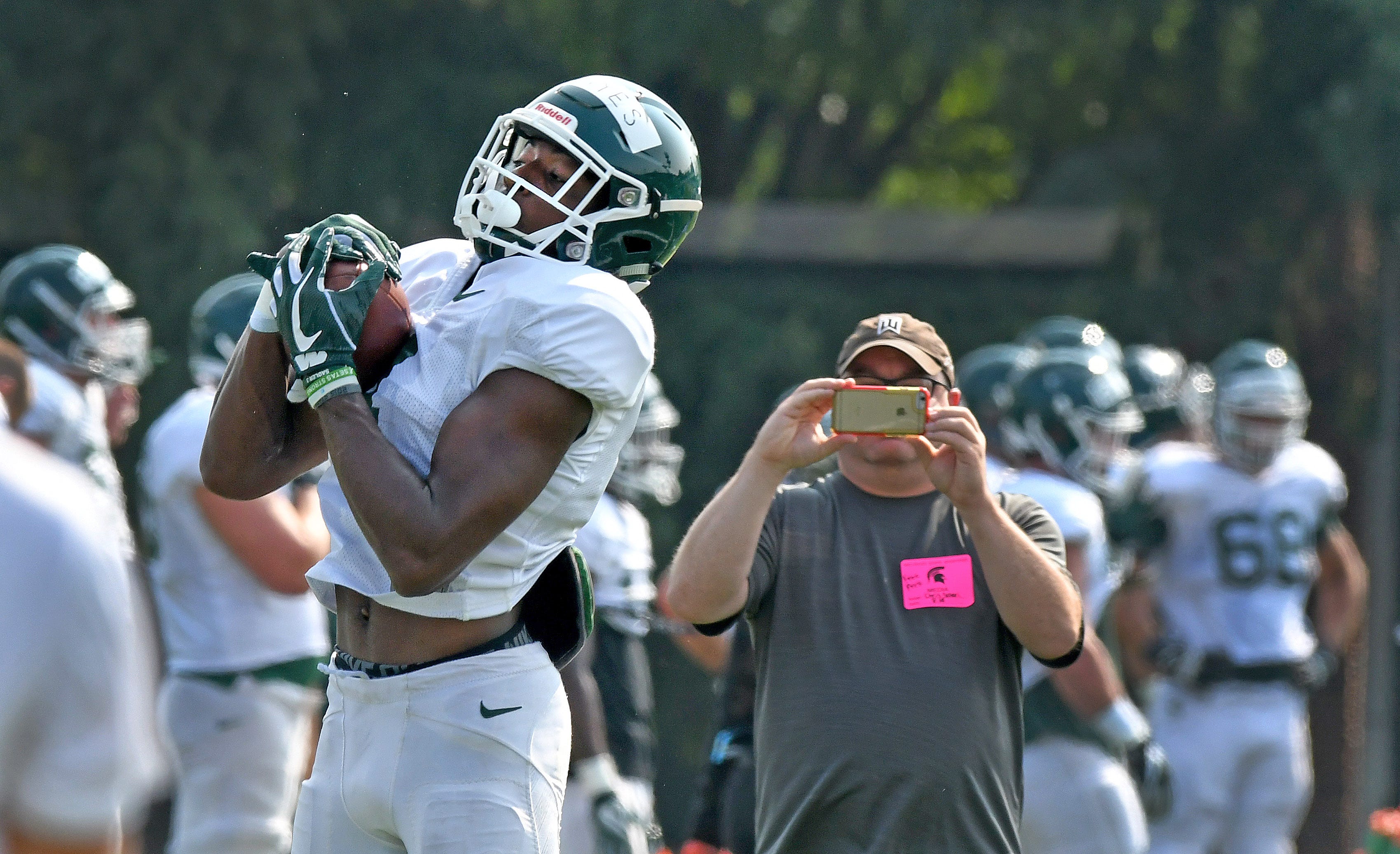 Michigan State receiver C.J. Hayes turns his back on a reporter to catch a pass.
