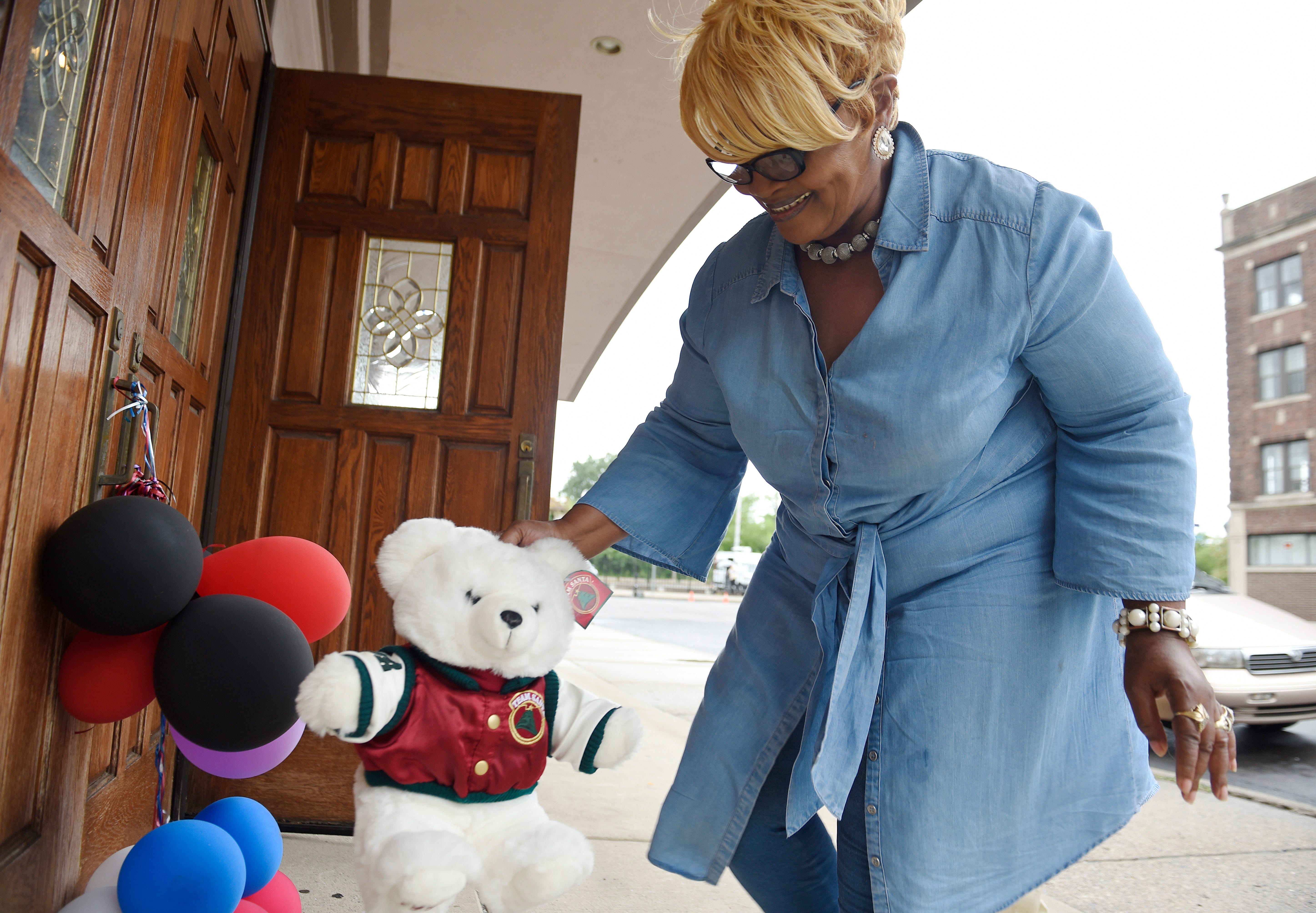 Sennettra Allen, 66, of Detroit pays her respects by leaving a teddy bear at a makeshift memorial outside New Bethel Baptist Church in Detroit, Aug. 16, 2018.