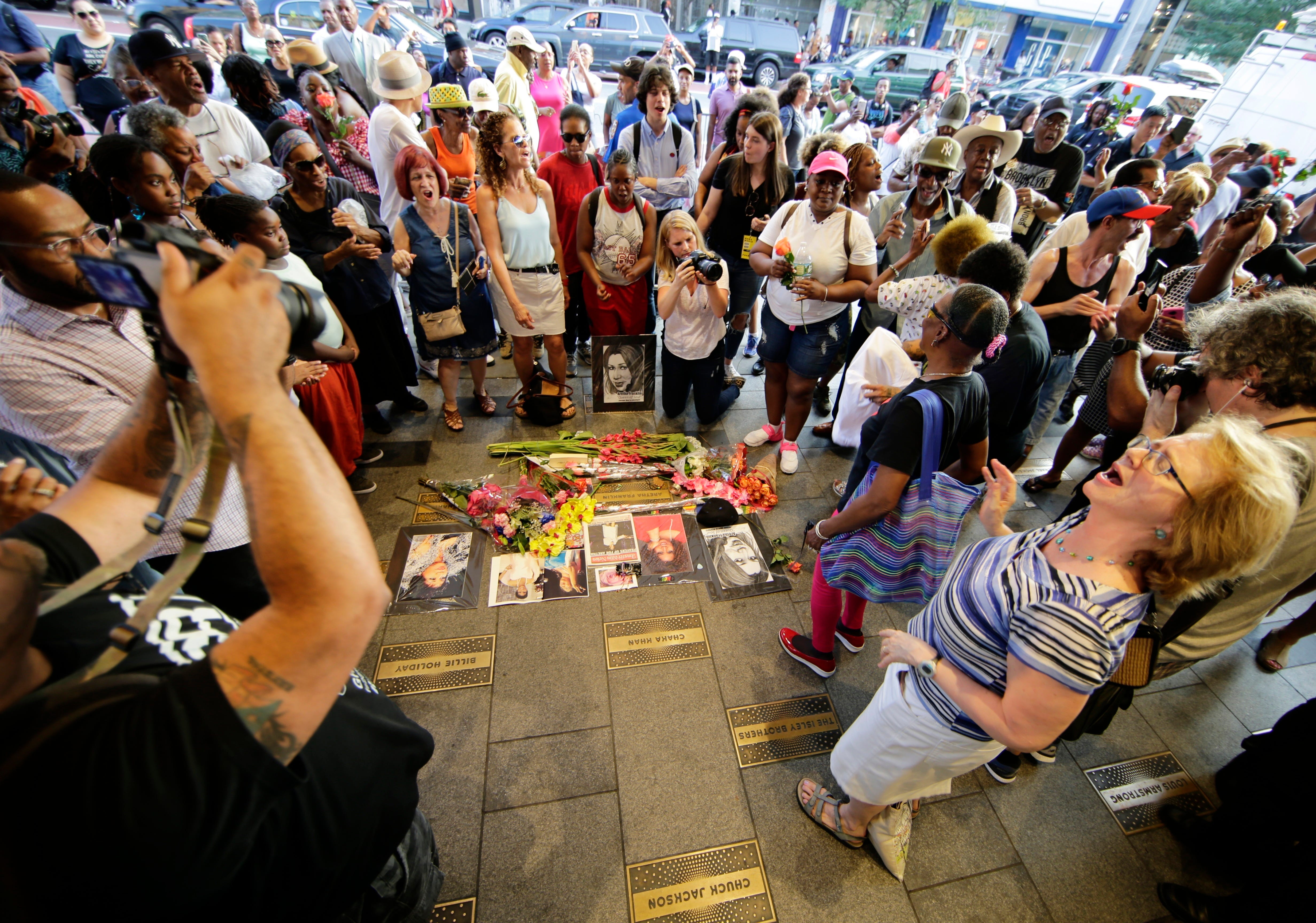 People dance and sing at a makeshift memorial for singer Aretha Franklin outside the Apollo Theater Thursday, Aug. 16, 2018, in New York. Franklin died in her home in Detroit at age 76 from pancreatic cancer. (AP Photo/Frank Franklin II)