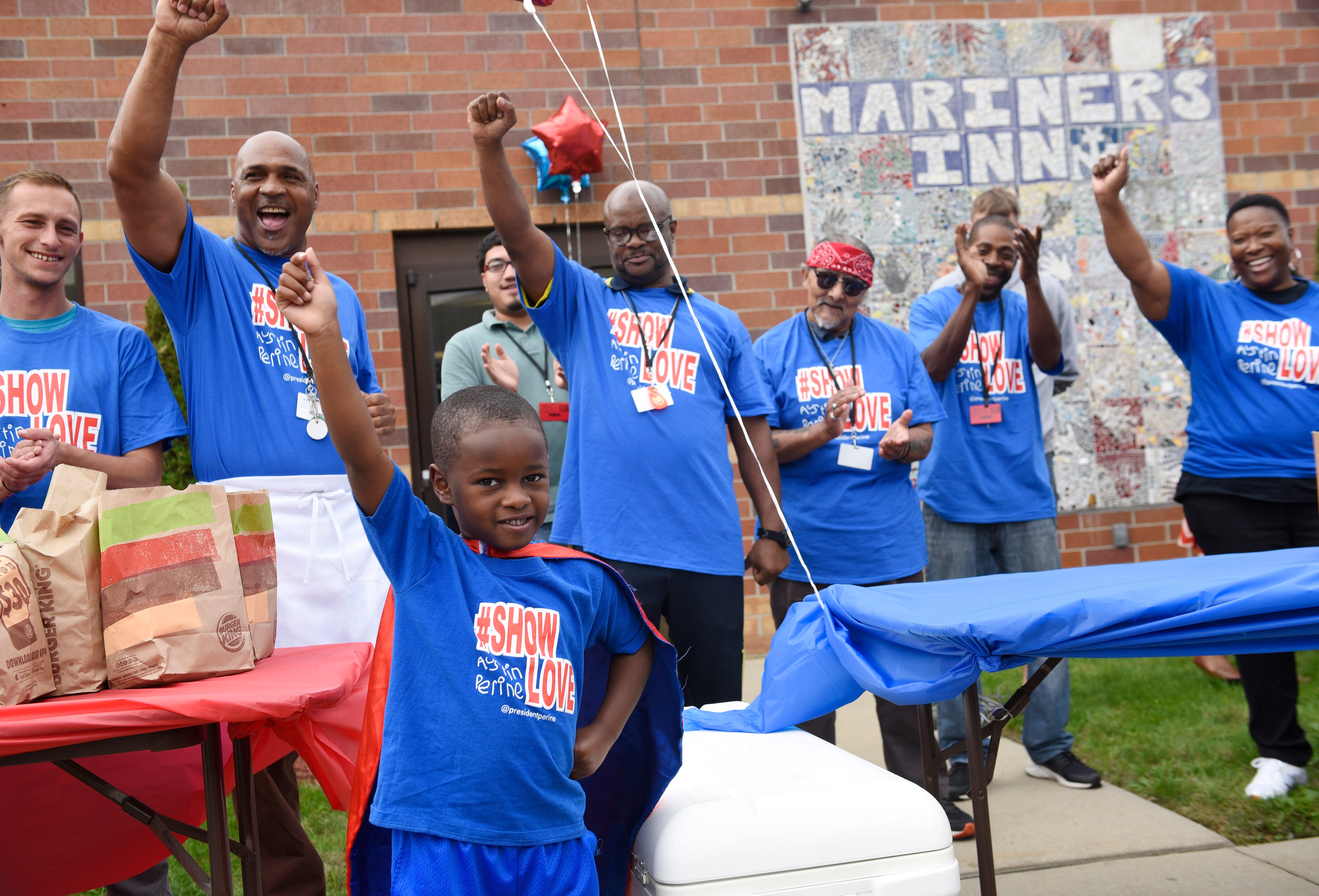 Austin Perine, 4, raises his hand to the applause from the crowd upon his arrival at Mariners Inn in Detroit.  Perine is a 4-year-old self-proclaimed superhero from Birmingham, Ala. His superpower is feeding as many homeless people as possible. Austin feeds the homeless on the streets and reminds them to show love to someone else.