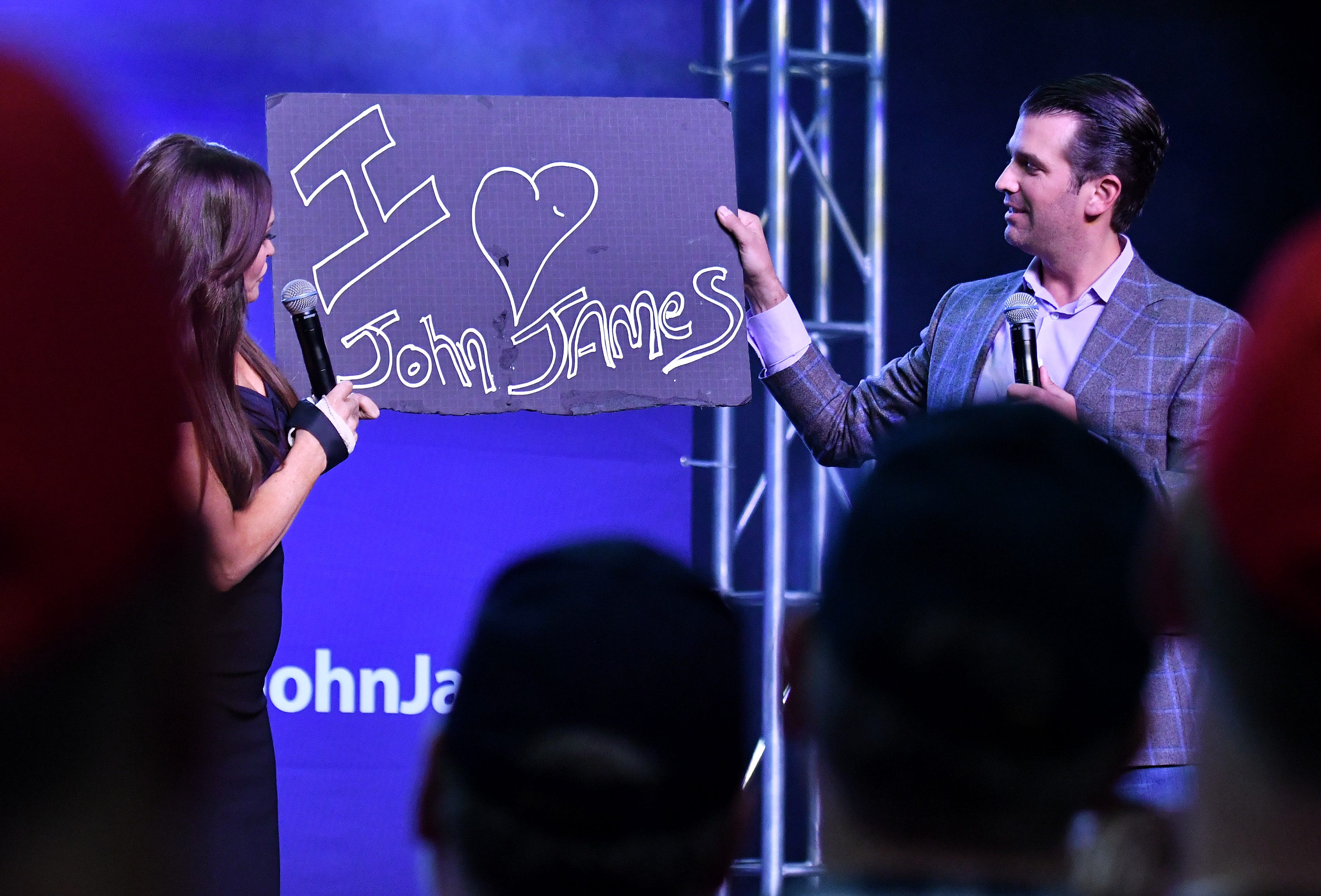 Donald Trump, Jr. right, and Kimberly Guilfoyle hold up a "I love John James" sign during the rally.
