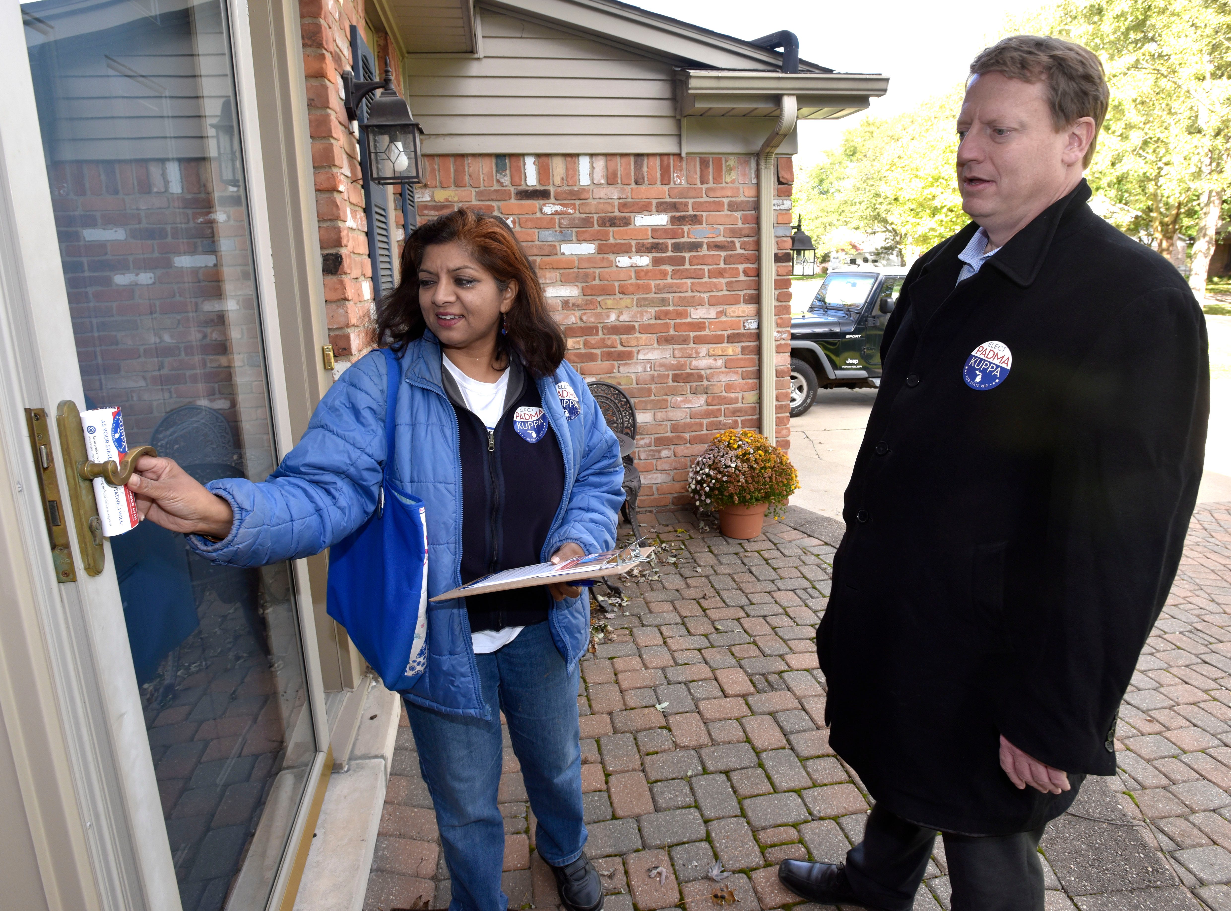 Padma Kuppa, a Democrat running for the 41st state House District that includes Troy and Clawson, puts a flyer in a door while campaigning in Troy with Tim Greimel, minority leader of the state House.
