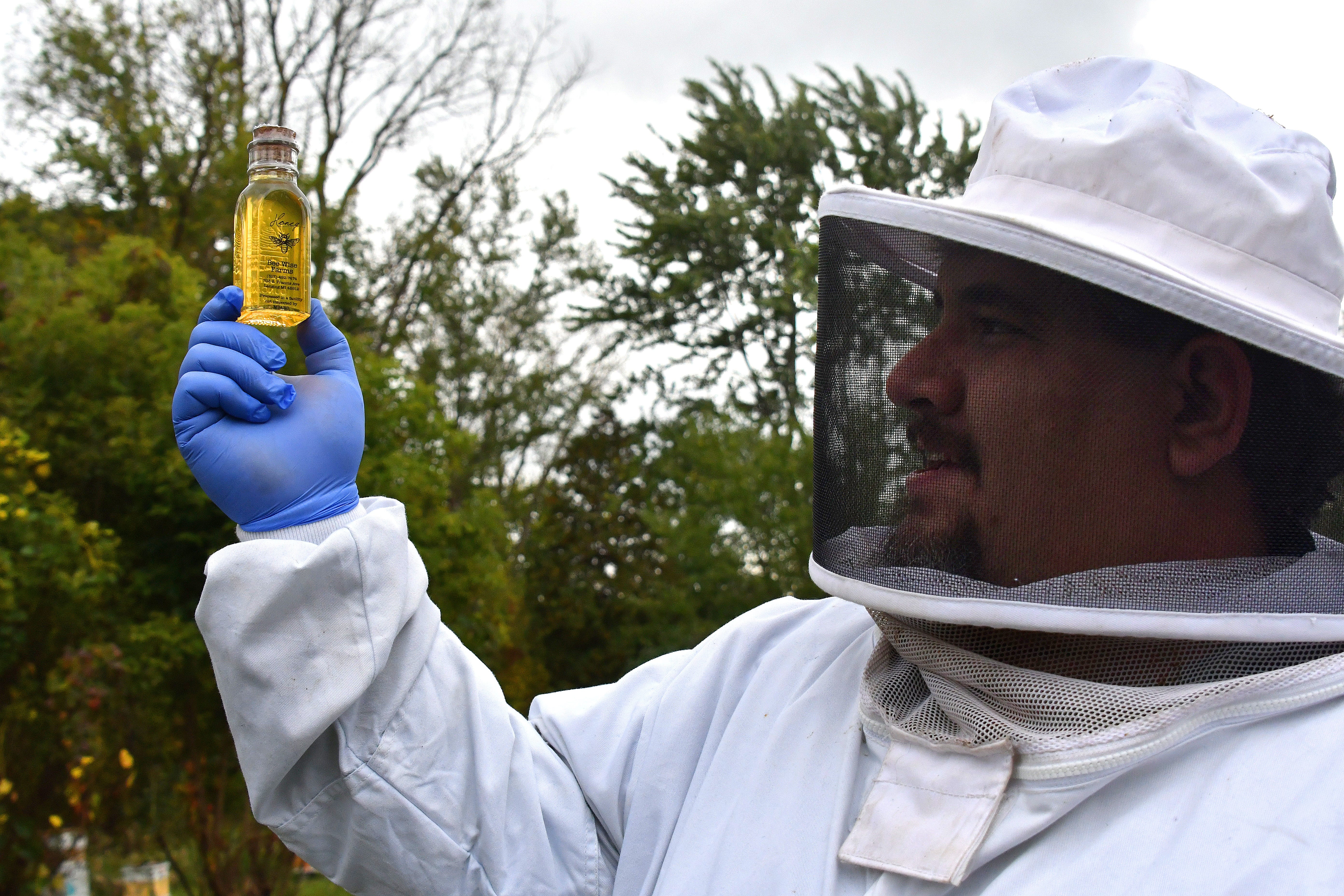 Marine Tom Kusar holds aloft and admires a bottle of fresh honey.