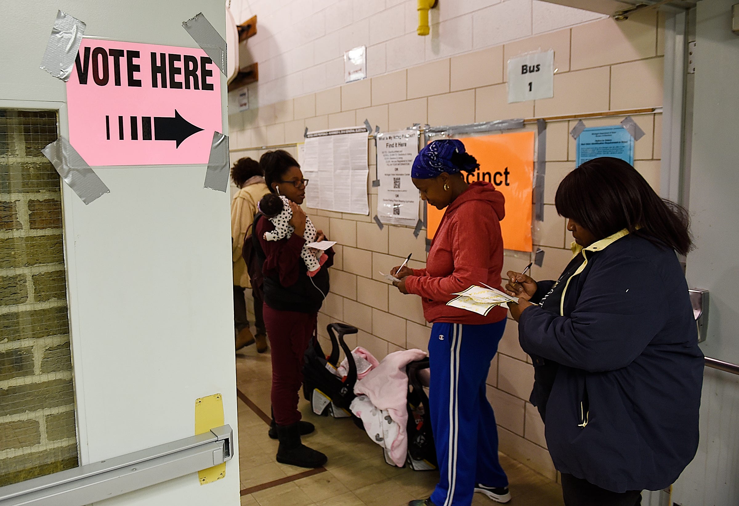 Vivien Mckenzie, 54, center, of Southfield and Sharon Carr, 62, of Southfield fill out applications to vote.