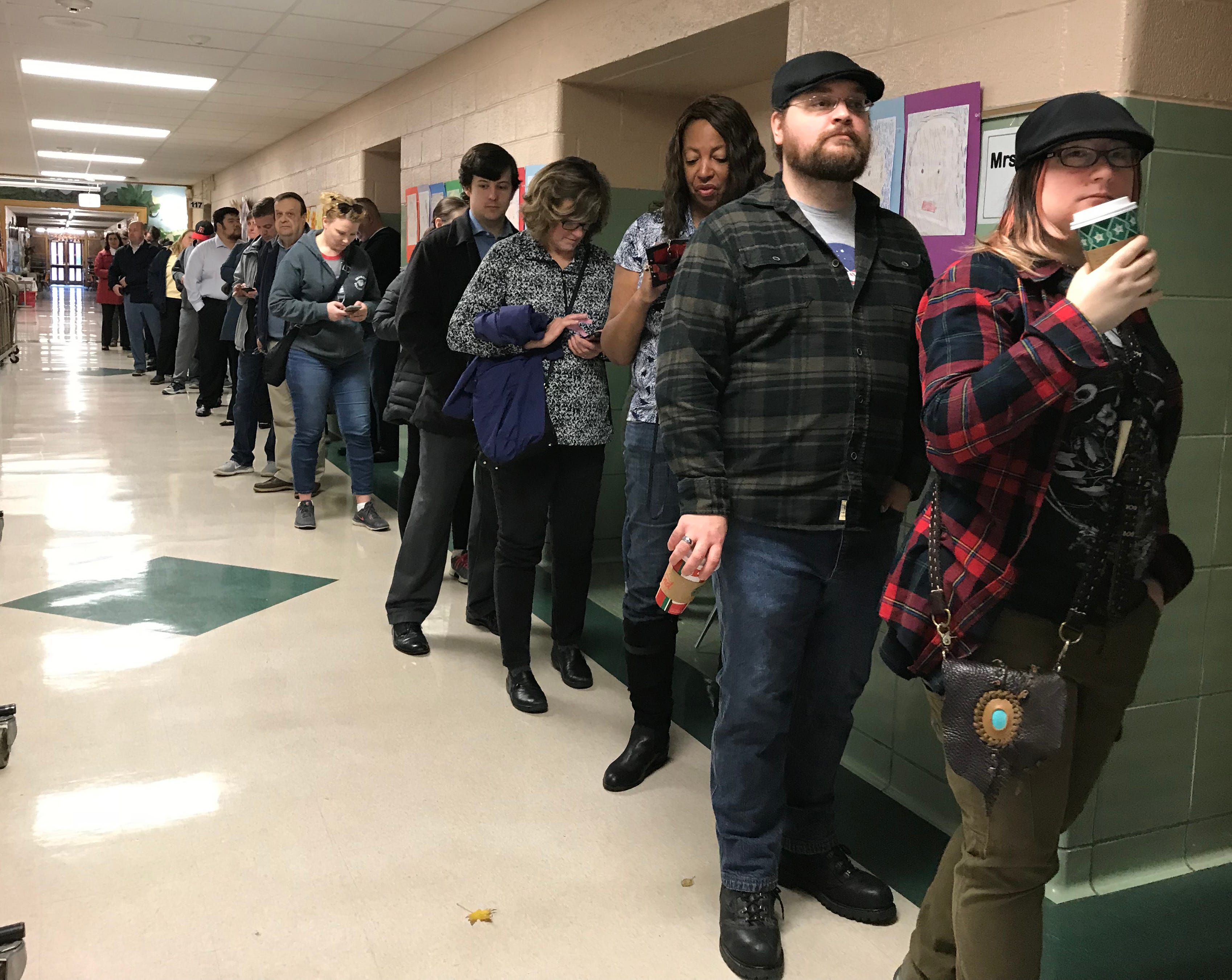 A long line of voters wait in the hallway outside the gymnasium at Monteith Elementary School to cast their ballots in the midterm election Tuesday morning in Grosse Pointe Woods, Michigan.