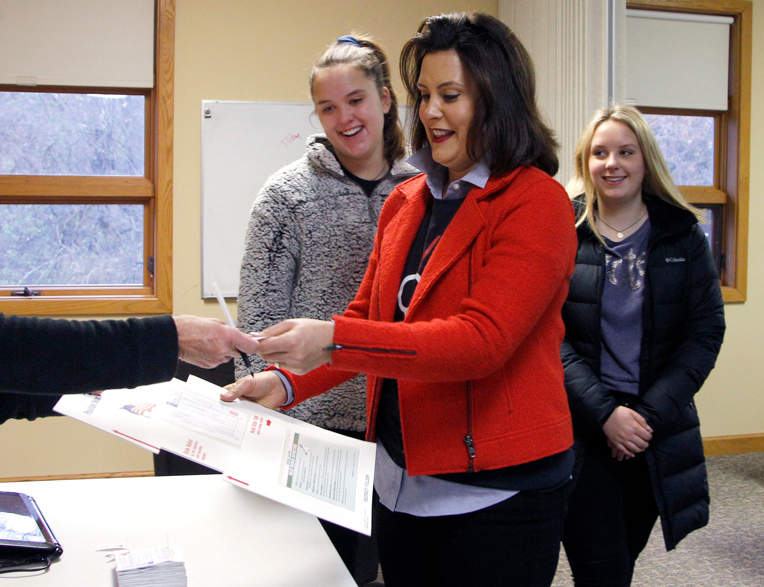 Michigan Democratic gubernatorial candidate Gretchen Whitmer, with daughters Sherry, left, and Sydney, right, turns in her privacy folder and receives a sticker after casting her ballot, Tuesday, Nov. 6, 2018, at St. Paul Lutheran Church in East Lansing.