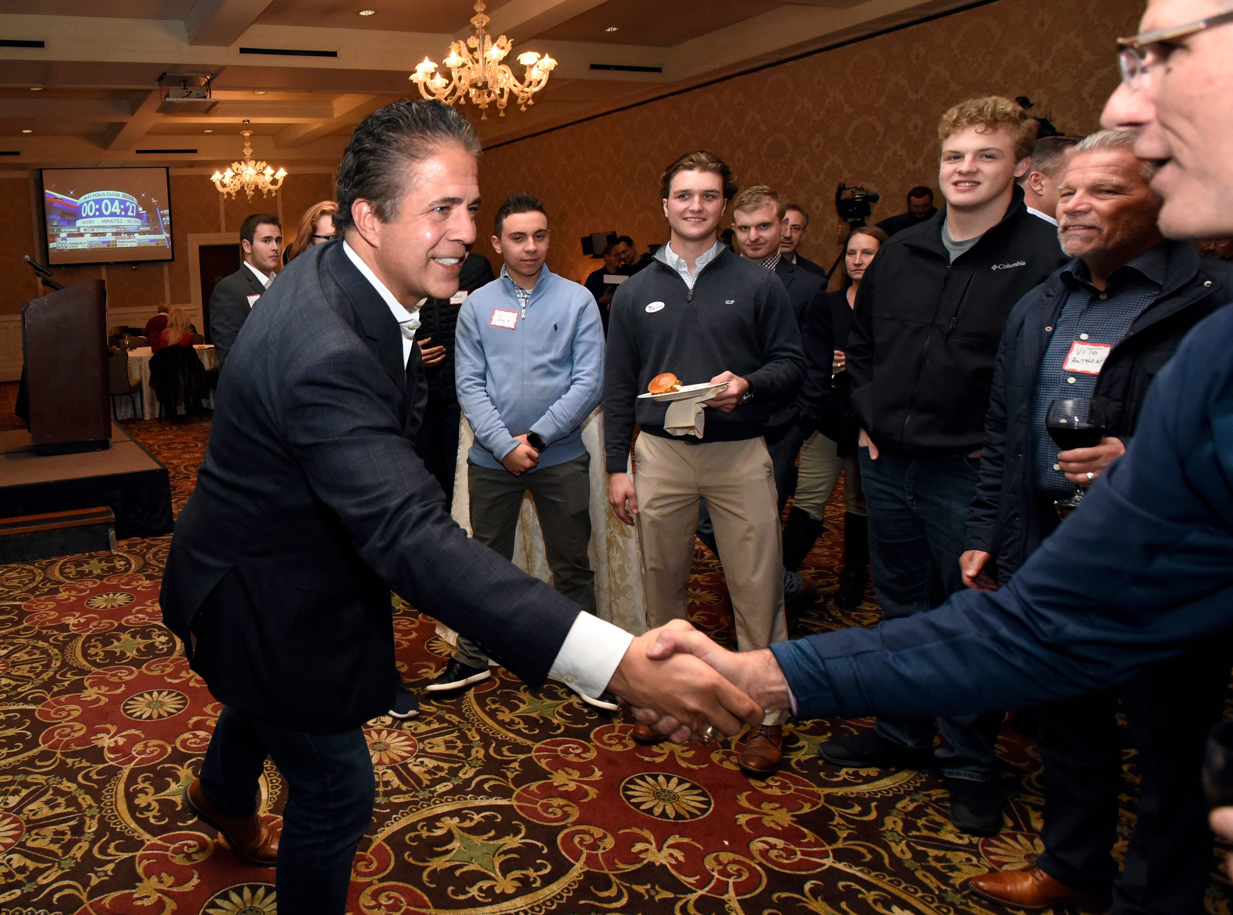 Rep. Mike Bishop, R-Mich., left, shakes hands at his campaign watch party with supporter Tommy Saracino in Rochester, Tuesday.