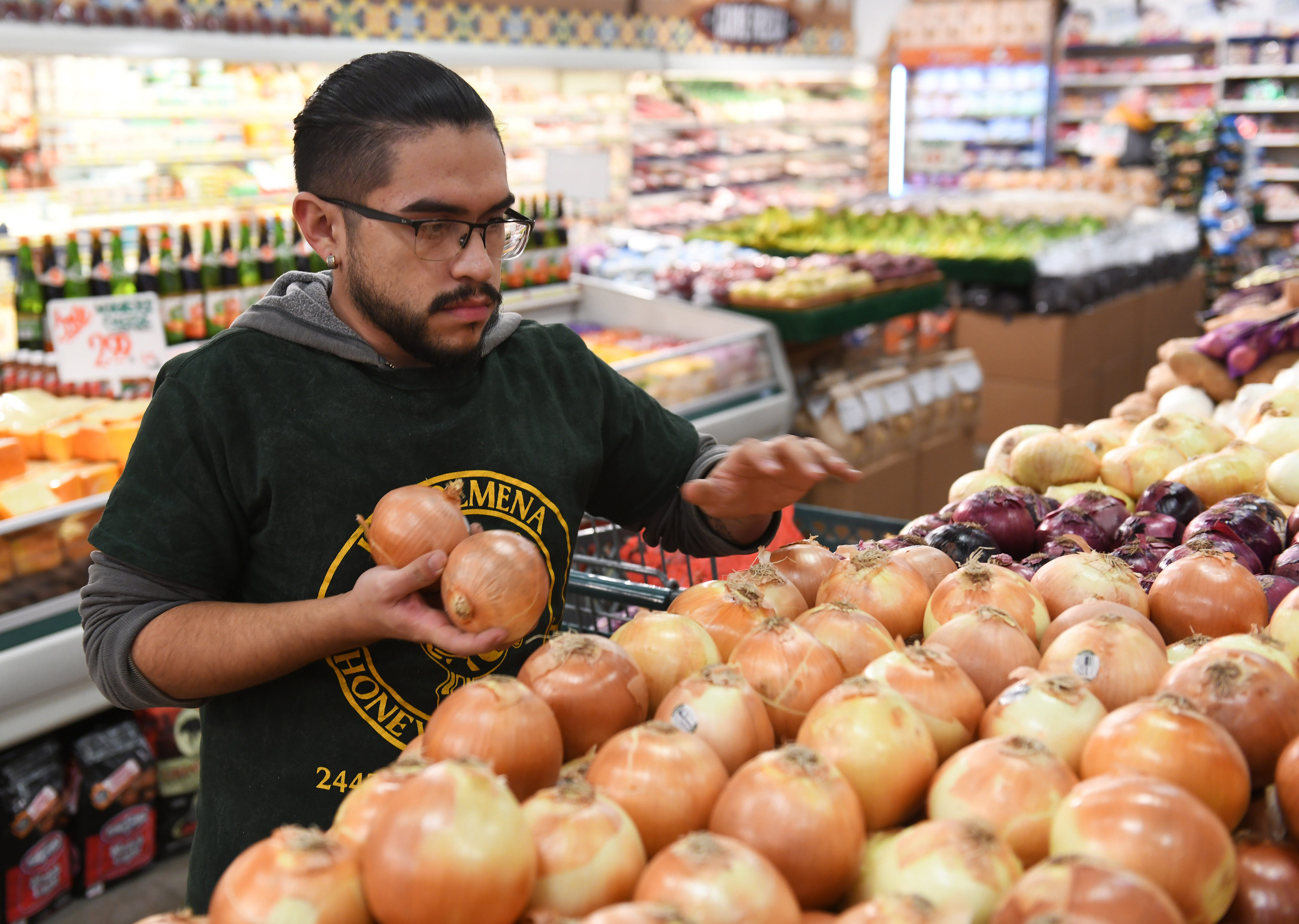 Luis Nino, 21, of Detroit, stocks produce at Honey Bee Market in Detroit on Thursday. The manager says they are hiring for the holiday season.