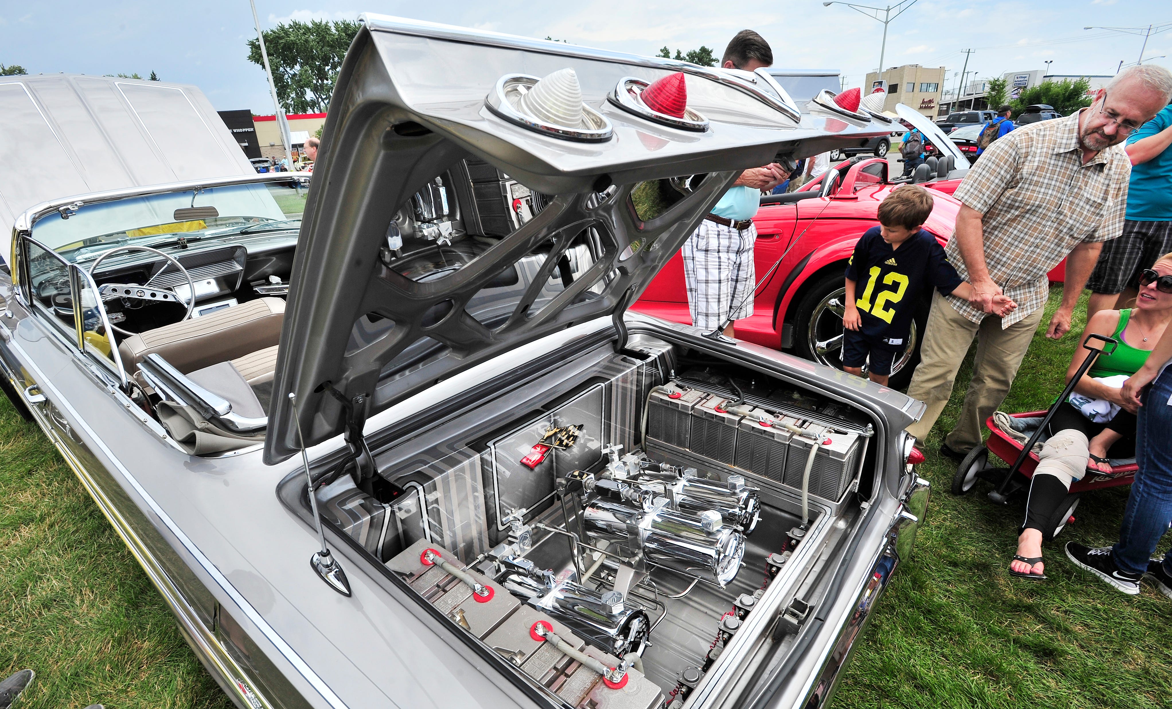 An open trunk of an Impala with batteries and hydraulics draws stares. "A '61 amazing Impala" says Daniel Zaid as he looks over the spotless, chromed-out engine during the Woodward Dream Cruise in Royal Oak, Aug. 16, 2014.