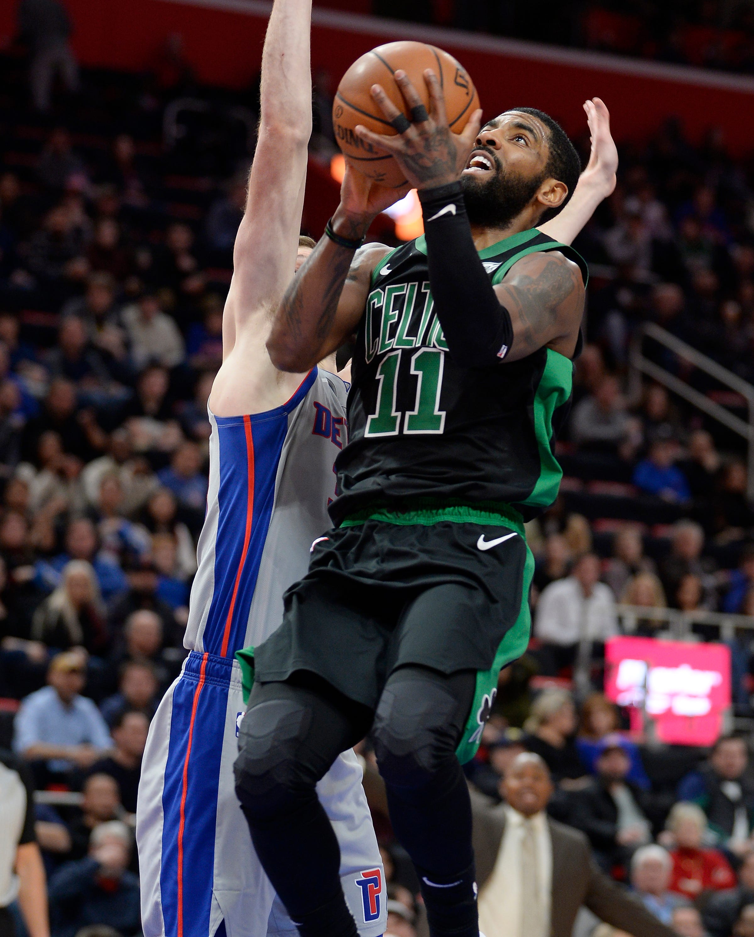 Celtics ' Kyrie Irving scores over Pistons ' Jon Leuer in the first quarter.