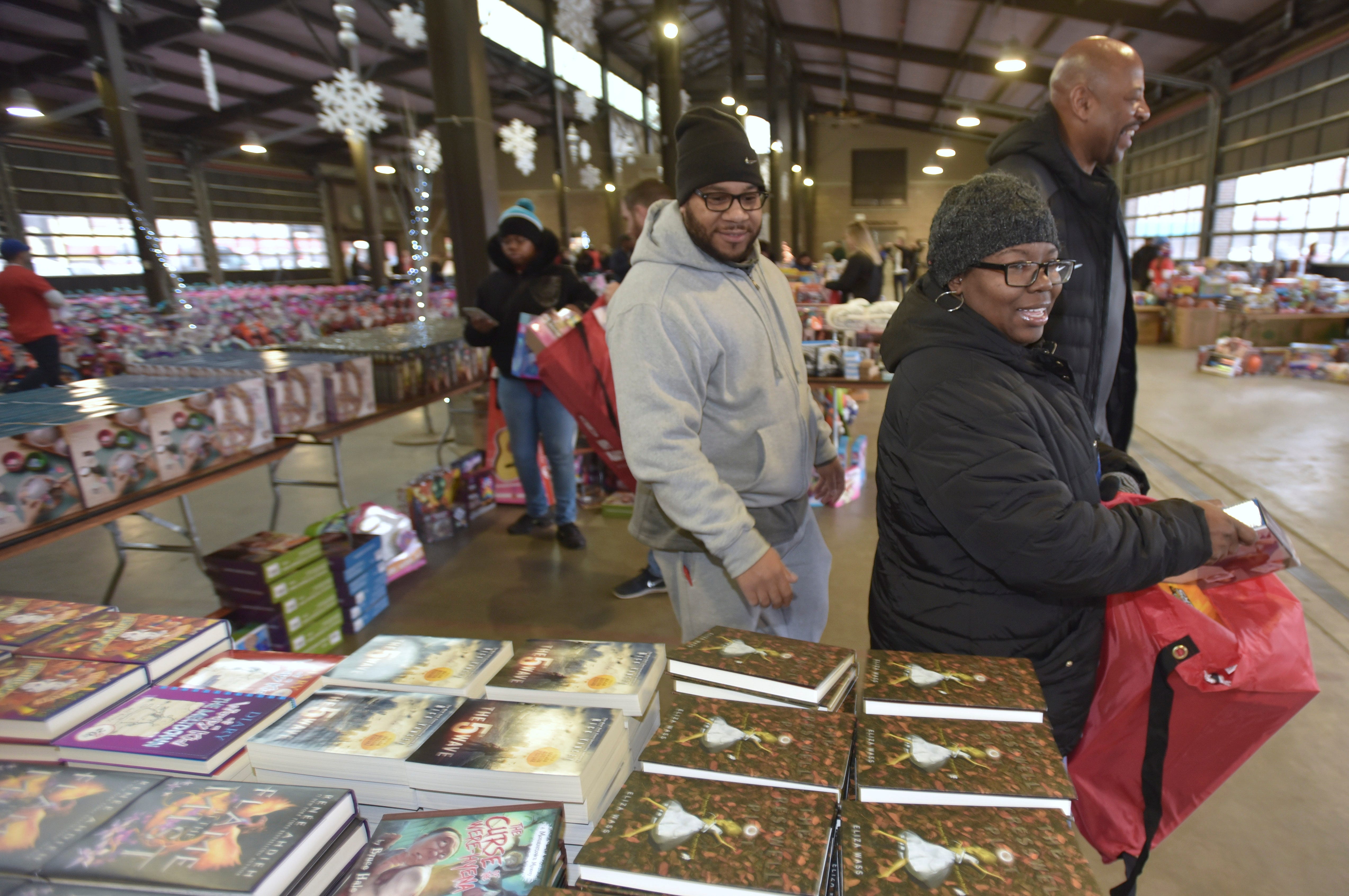 Pistons legend and community ambassador Earl Cureton, right, shares a laugh with Cheri Lynch, center, and her husband, Angelo Lynch, left, both of Detroit, as they shop for Christmas presents.