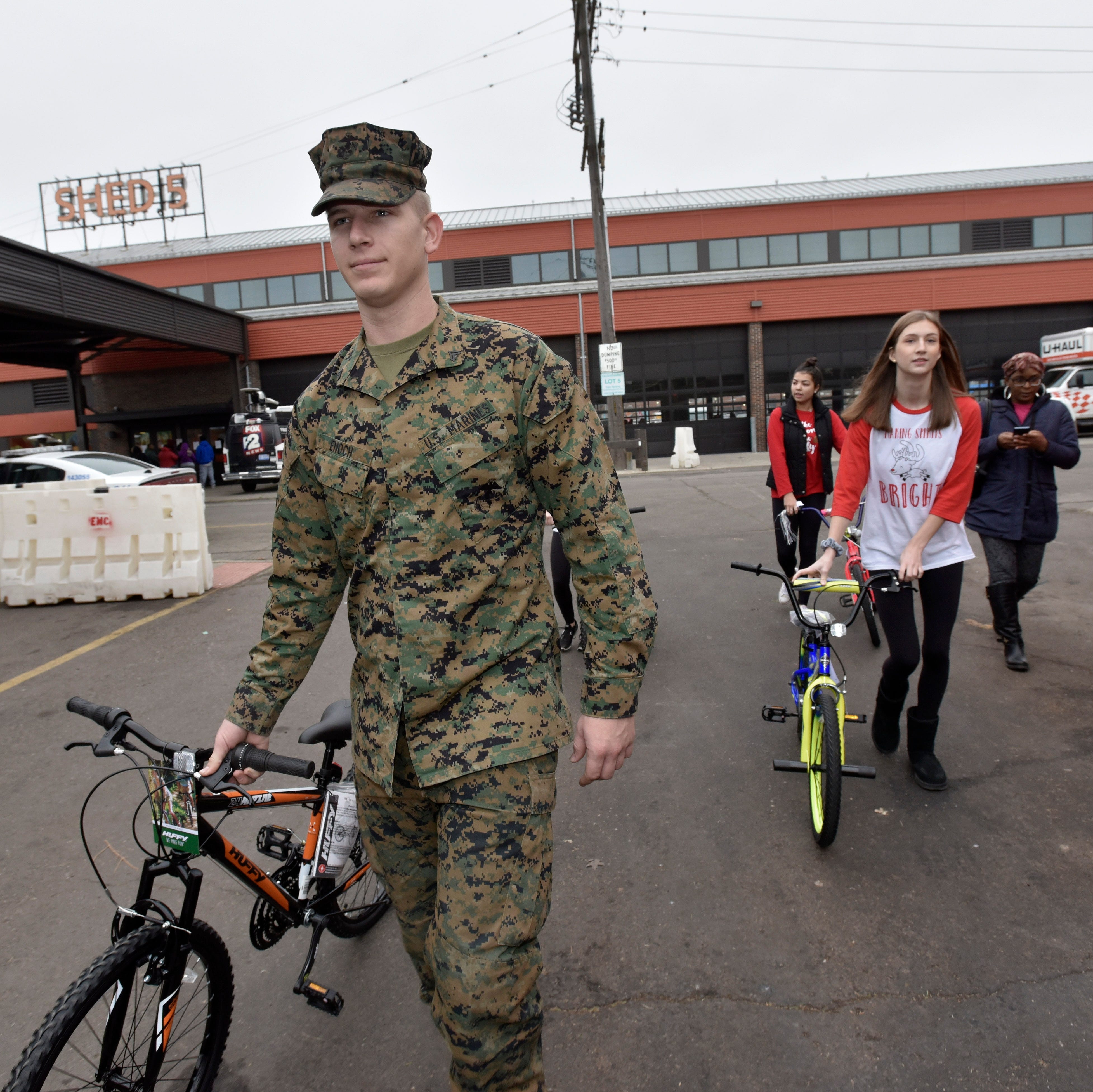 Corporal Asher Enoch, left, and others wheel bicycles to the vehicle of Bianca Robinson, right, of Detroit after she and her husband, Juan Bell (not pictured) shop for their four kids.