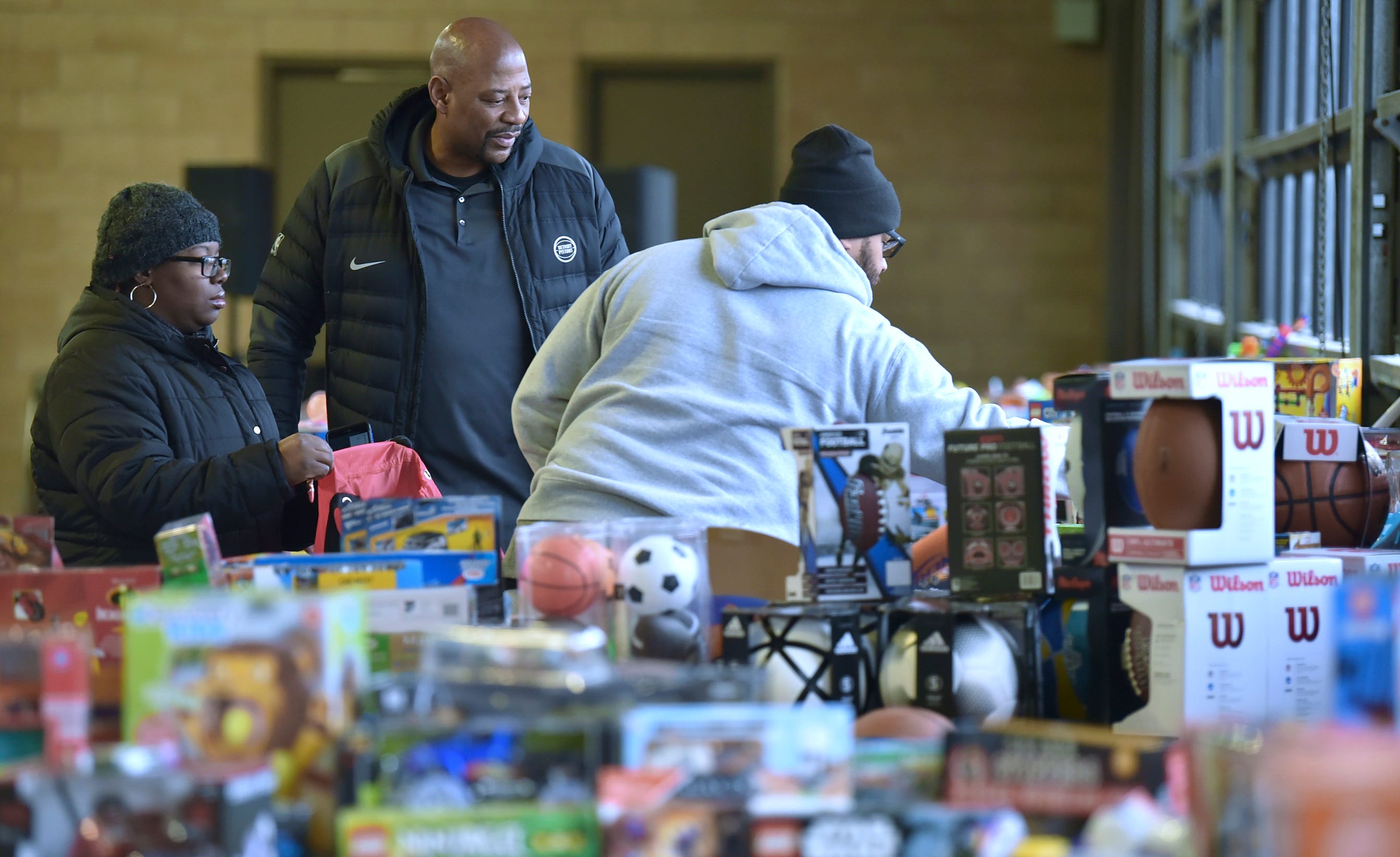 Pistons legend and community ambassador Earl Cureton, center, helps Cheri Lynch, left, and her husband, Angelo Lynch, both of Detroit, shop for Christmas presents.