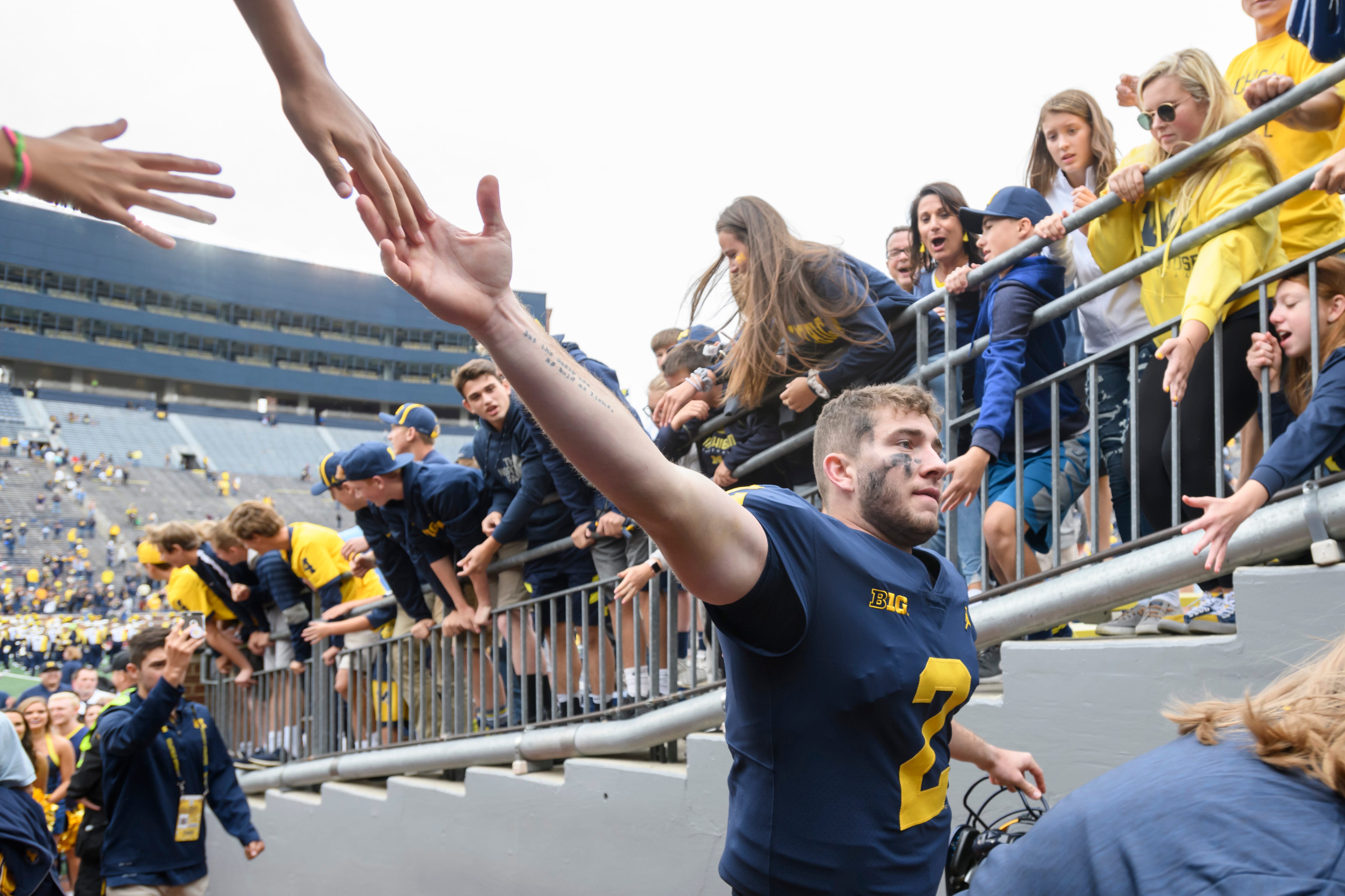 Michigan quarterback Shea Patterson gets high-fives from the fans as he walks through the tunnel after the game against Western Michigan.