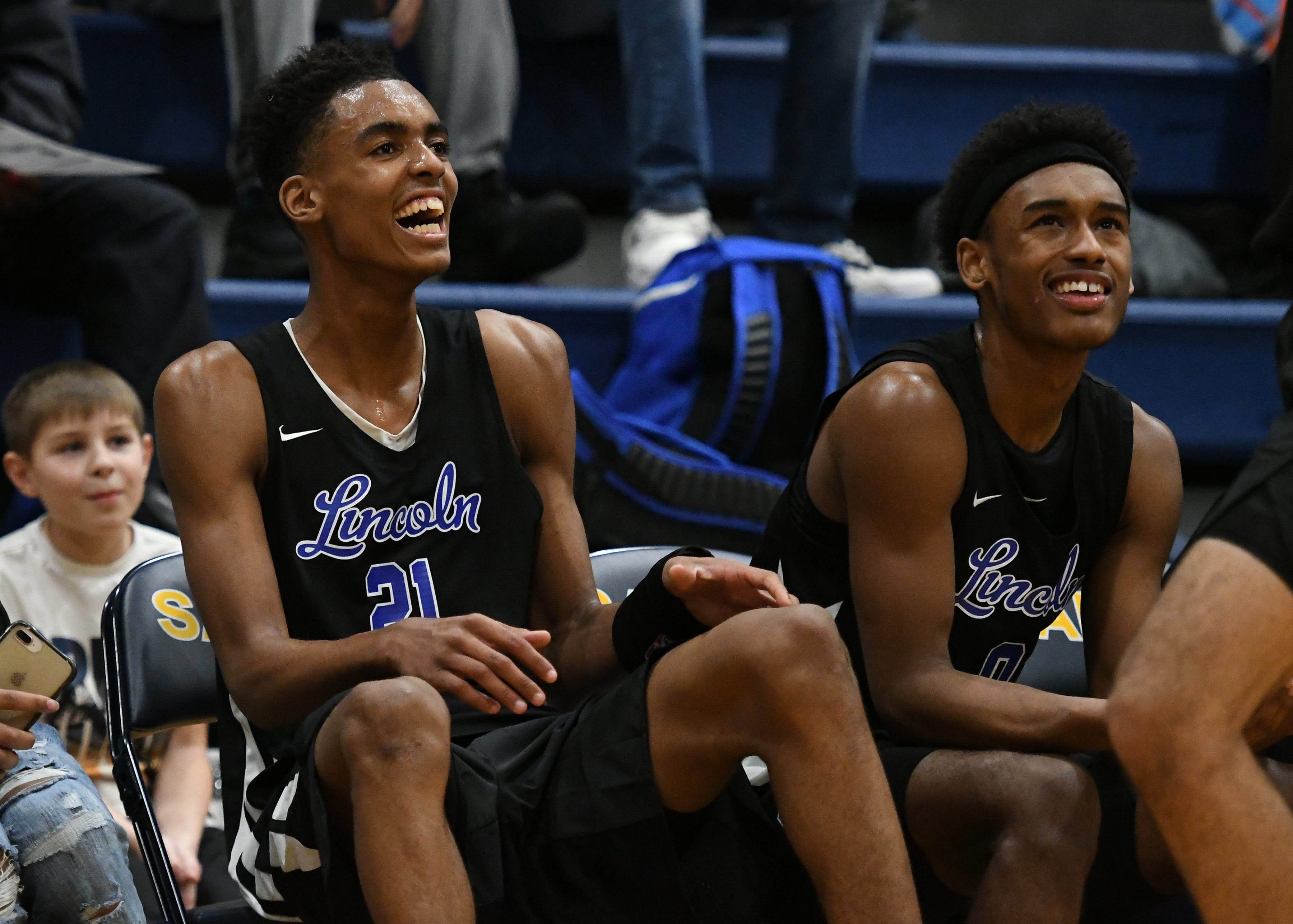 Emoni Bates, left, enjoys watching the final minutes of Lincoln's 70-39 win over Saline from the bench.