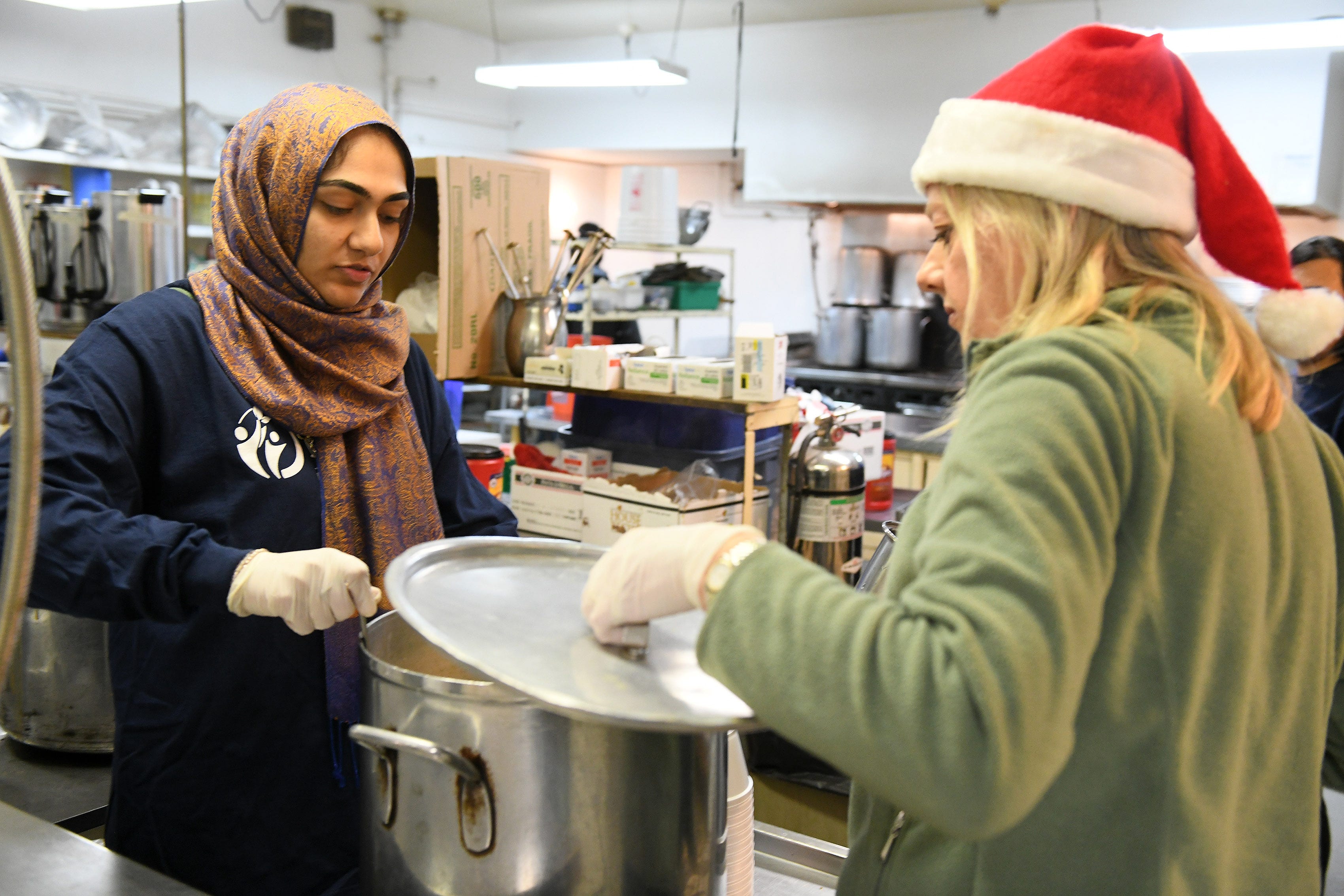 Mercy-USA for Aid and Development volunteer Hibah Naseer  22 of Canton, left, checks on a pot of soup with volunteer from Northville, Karen Schaumann. Muslim volunteers organized by Mercy-USA for Aid and Development serve food at St. Peter's Episcopal Church in Detroit on Dec. 24, 2018.