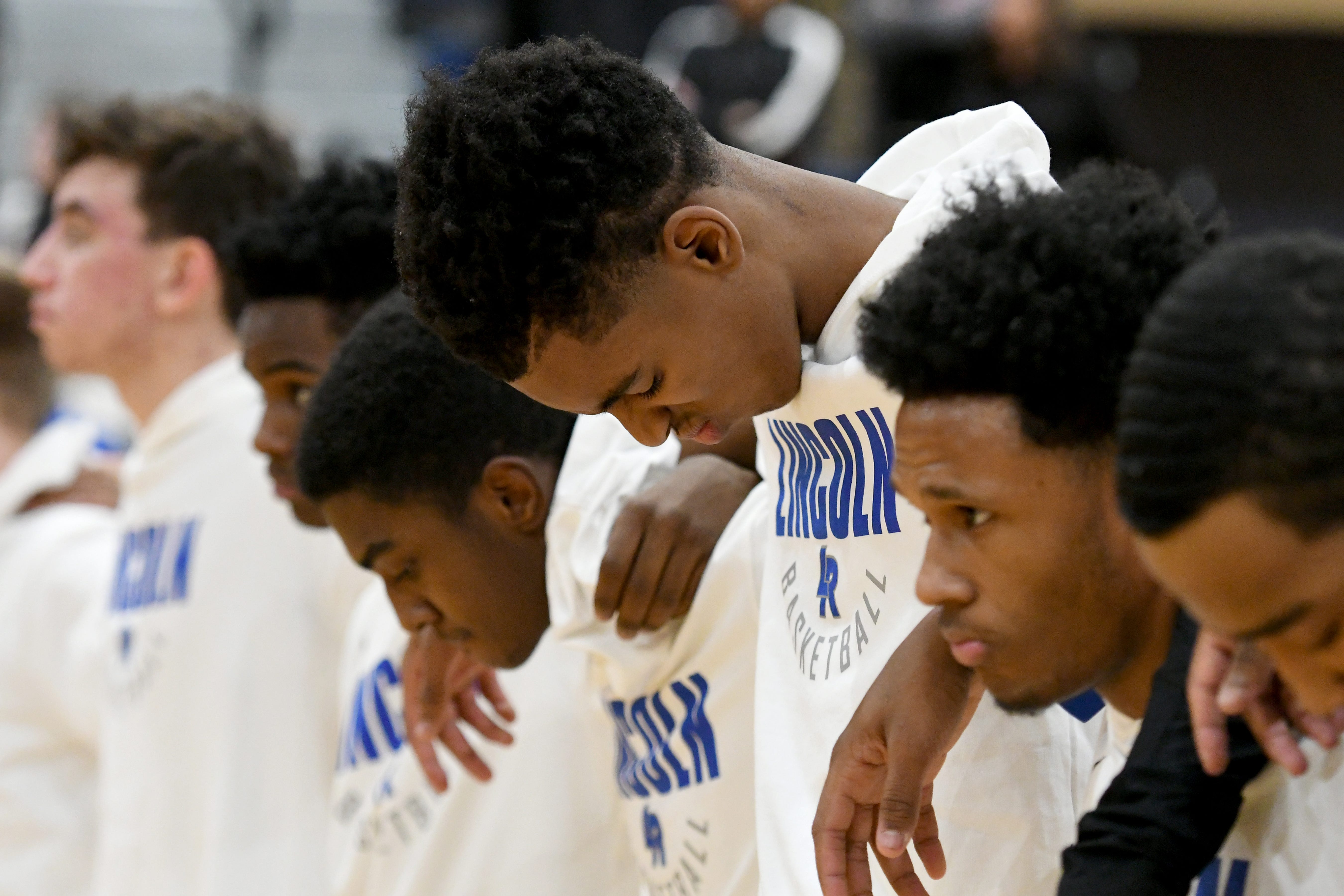 Emoni Bates, center, stands with his teammates during the National Anthem prior to their game against Saline High School.