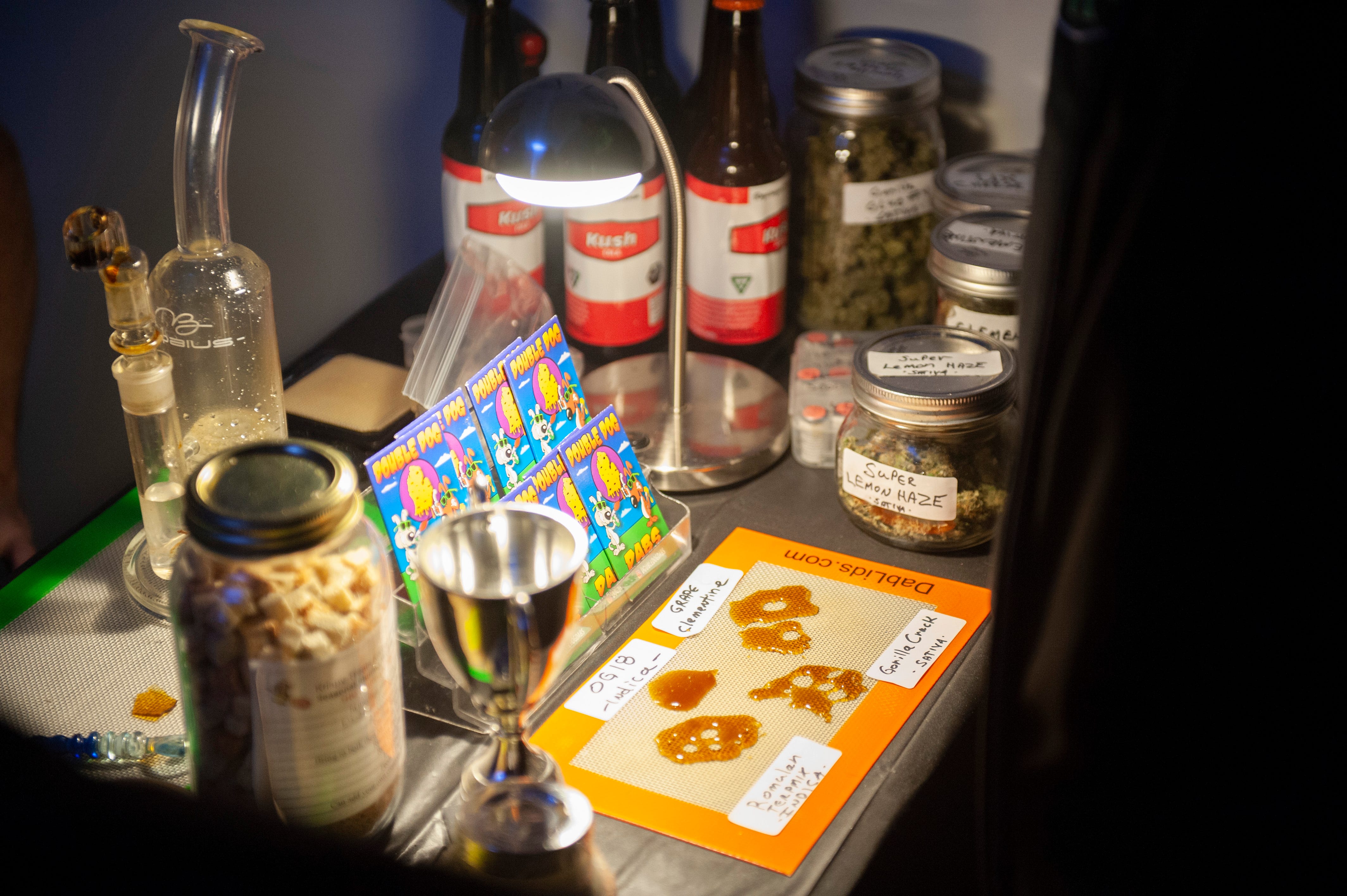 Double Dog Dabs display of cannabis products including "dabs," which are condensed THC resins usually smoked in a glass bong and various strains of marijuana buds and THC-infused Kush Cola at "The Art of Cannabis" event.