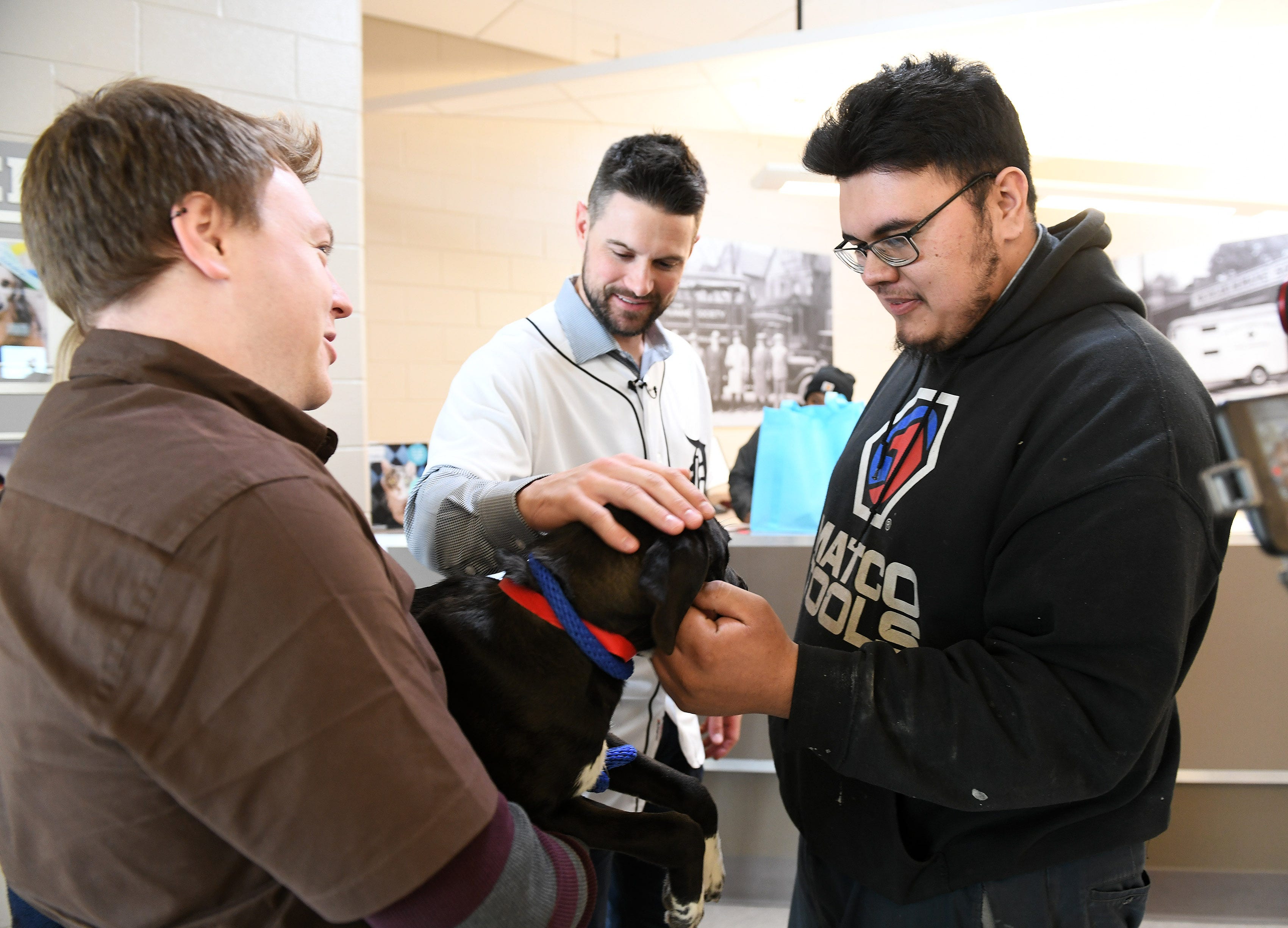 While Michigan Humane Society animal transport driver Jeremy Colborn holds her, Tigers shortstop Jordy Mercer and Marcelo Alvarado, 24, of Detroit, right, pet Lark, a Labrador that Marcelo is adopting, during a stop on the 2019 Detroit Tigers Winter Caravan at the Michigan Humane Society in Detroit on Jan. 25, 2019.