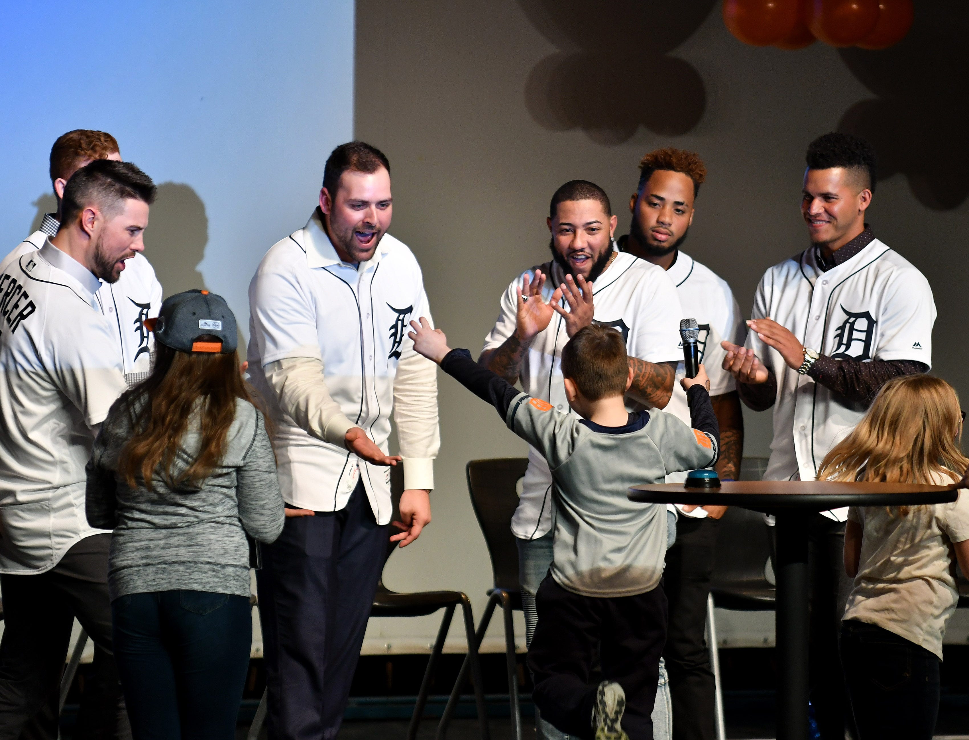 Tigers pitcher Michael Fulmer, second from left, and other Tigers high five James MacFarlane, 6, of Milford while they play a Tigers trivia game at a kids rally at Novi High School.