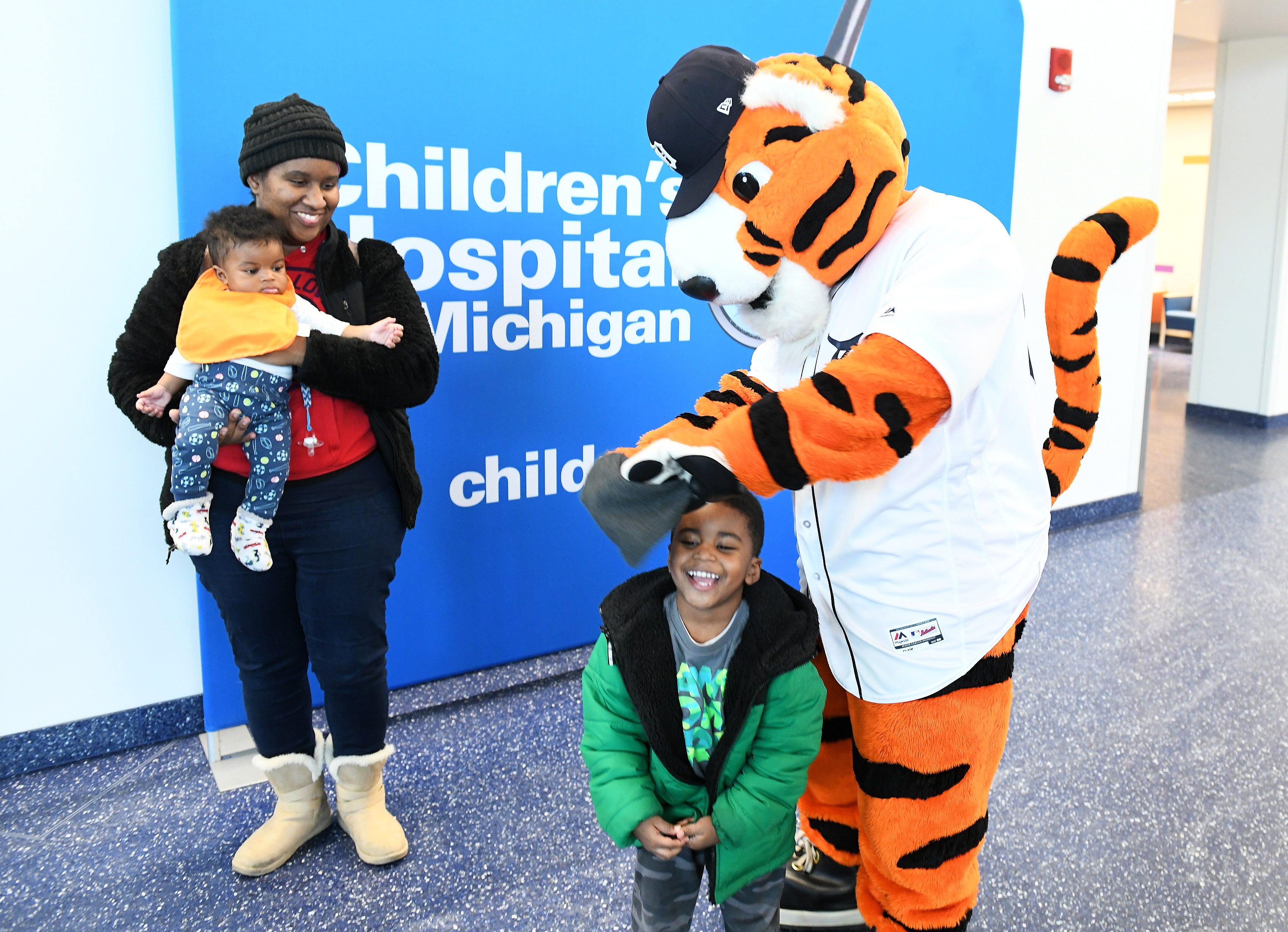 Paws plays with the hat of Domani Dixon, 3, with his mom, Demetria Dixon, left, and Maxwell Dixon, 6 months, at the Children's Hospital of Michigan.